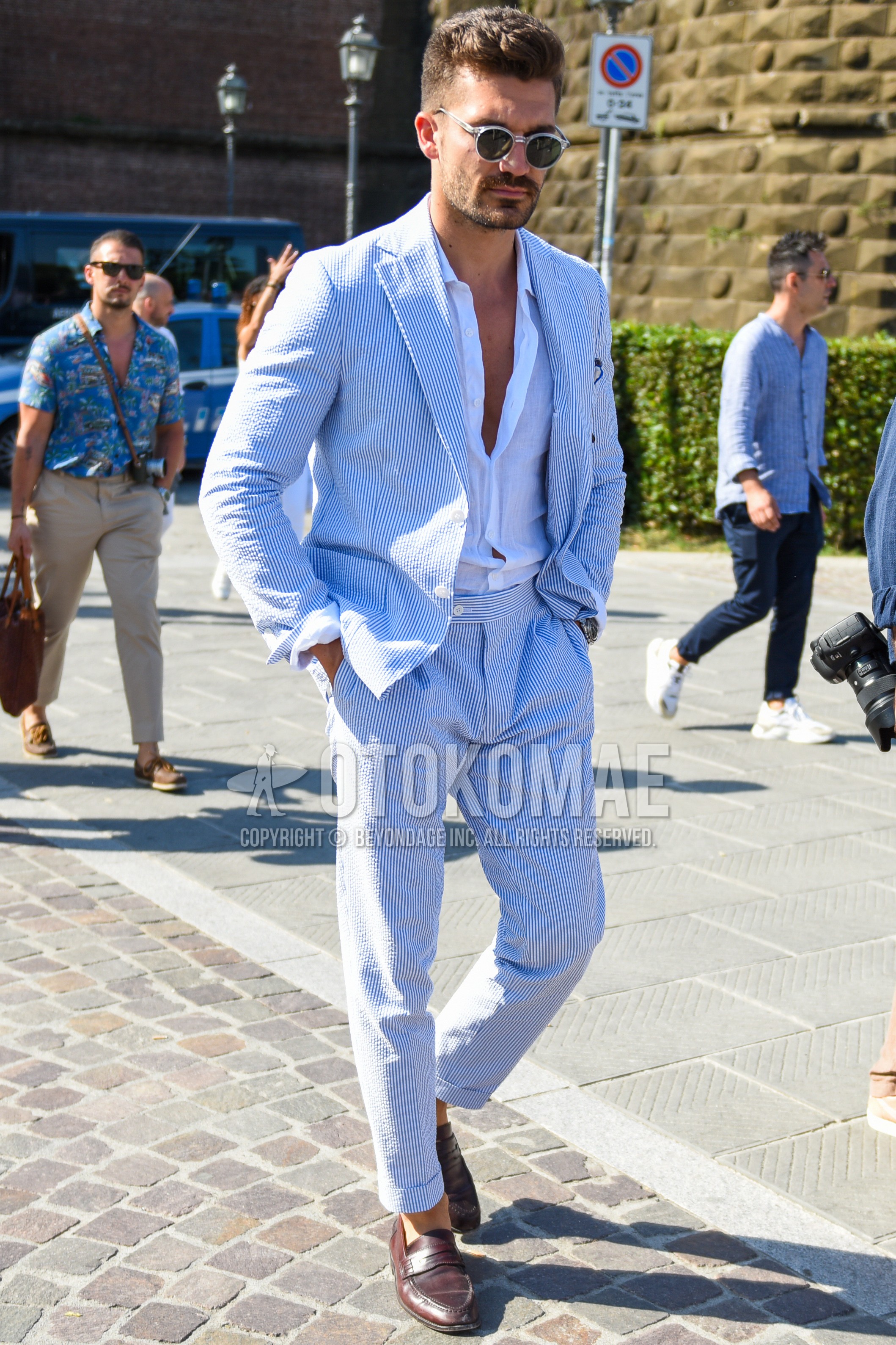 Men's spring summer autumn outfit with silver plain sunglasses, white plain shirt, brown coin loafers leather shoes, blue white stripes suit.