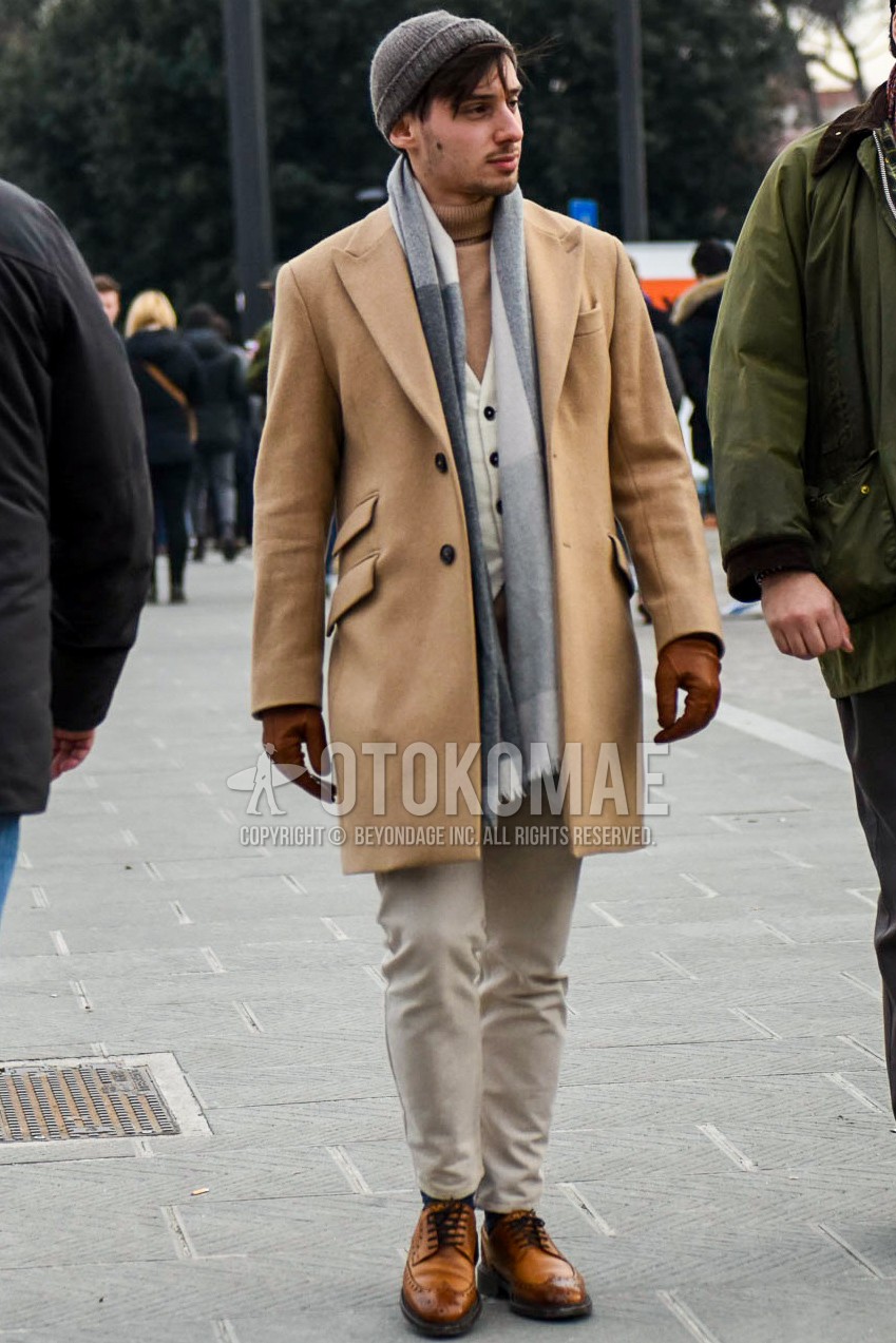 Men's winter outfit with brown plain knit cap, gray plain scarf, brown plain chester coat, brown plain turtleneck knit, white plain gilet, beige plain chinos, brown brogue shoes leather shoes.