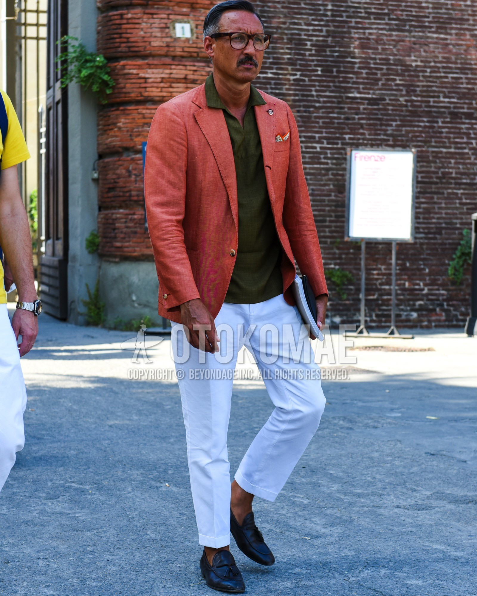 Men's spring summer outfit with brown tortoiseshell glasses, red plain tailored jacket, olive green plain polo shirt, white plain cotton pants, black tassel loafers leather shoes.