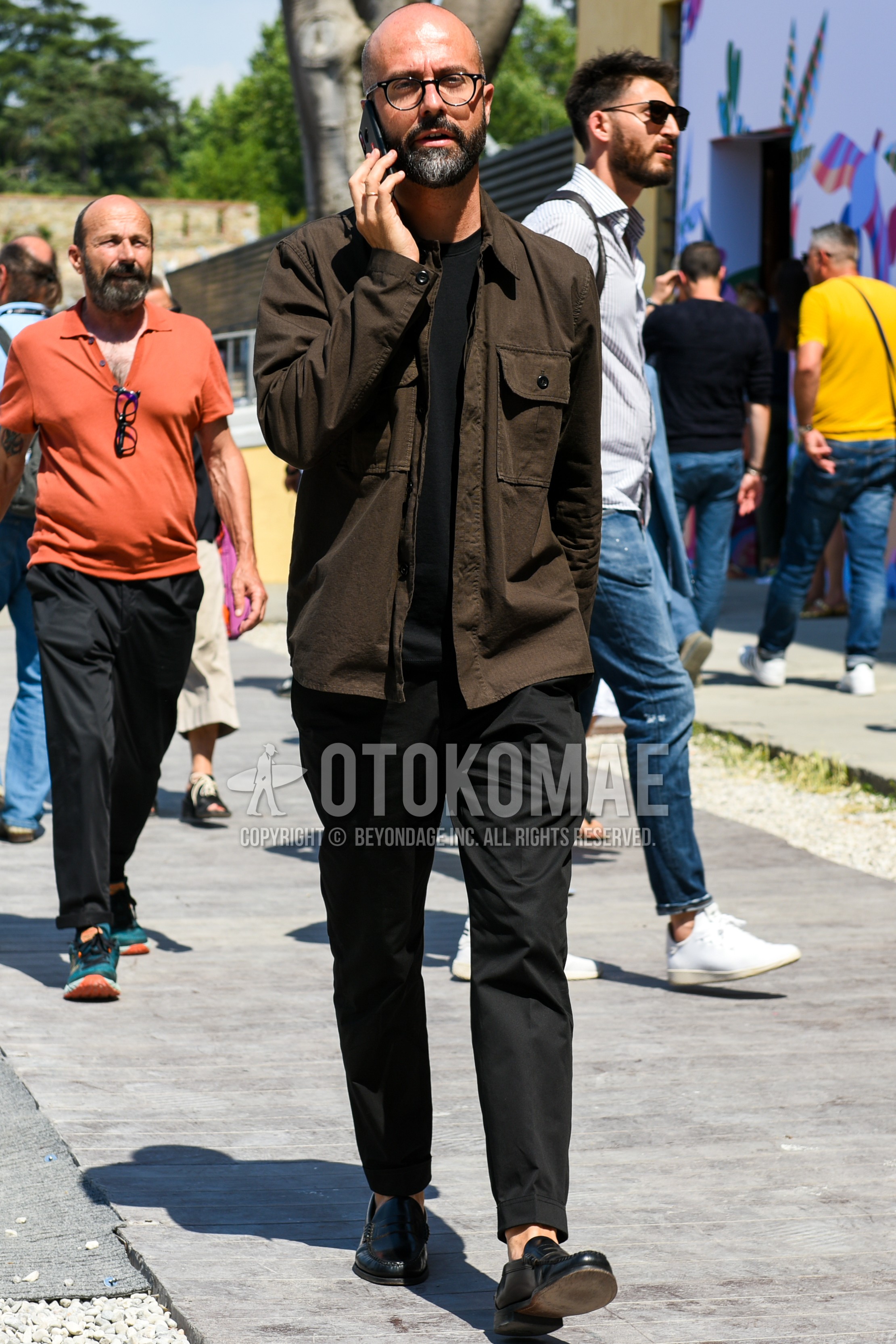 Men's spring summer outfit with black plain glasses, brown plain shirt jacket, black plain t-shirt, black plain ankle pants, black plain slacks, black coin loafers leather shoes.