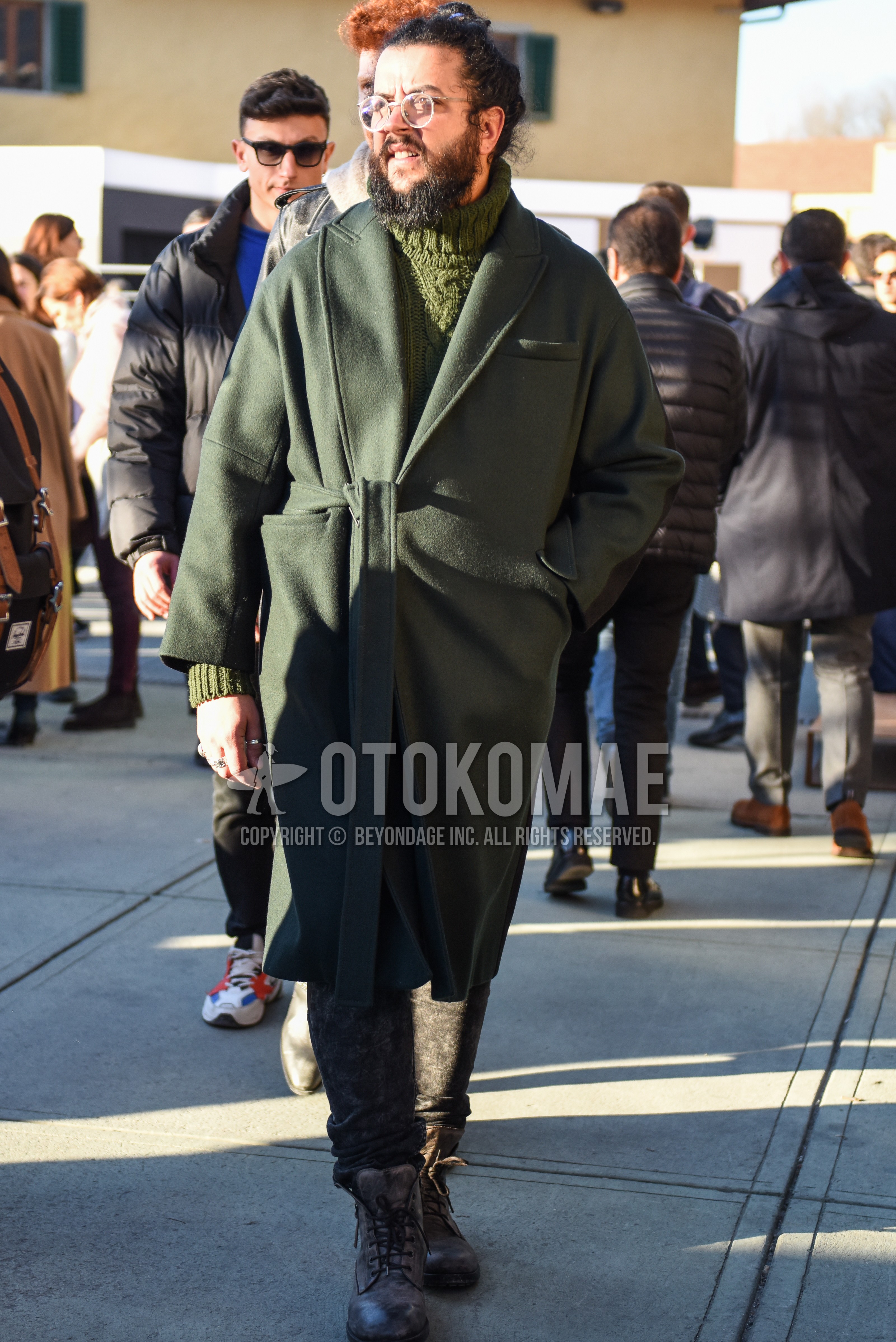 Men's autumn winter outfit with clear plain glasses, olive green plain chester coat, olive green plain belted coat, olive green plain turtleneck knit, gray bottoms slacks, brown work boots.