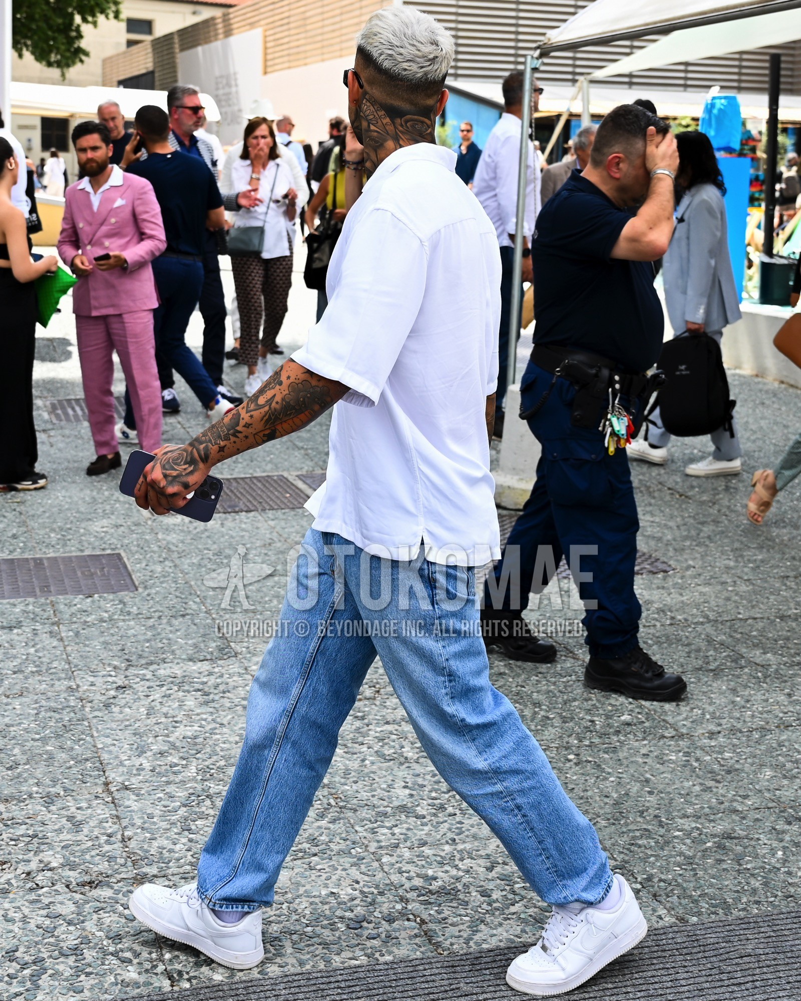 Men's spring summer outfit with white plain t-shirt, light blue plain denim/jeans, light blue low-cut sneakers.