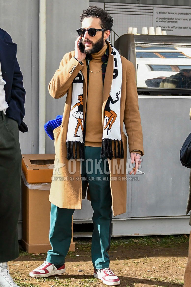 Men's winter outfit with plain sunglasses, white graphic scarf, brown plain chester coat, brown plain turtleneck knit, green plain cotton pants, red high-cut sneakers.