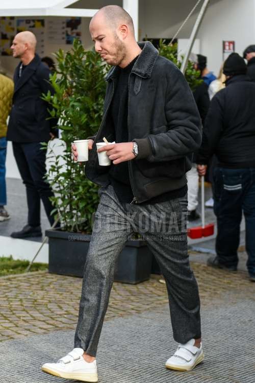 黒無地のレザージャケット(ライダース以外)、黒無地のセーター、グレーボトムスのスラックス、グレー無地のアンクルパンツ、白ローカットのスニーカーを合わせた秋冬のメンズコーデ・着こなし。