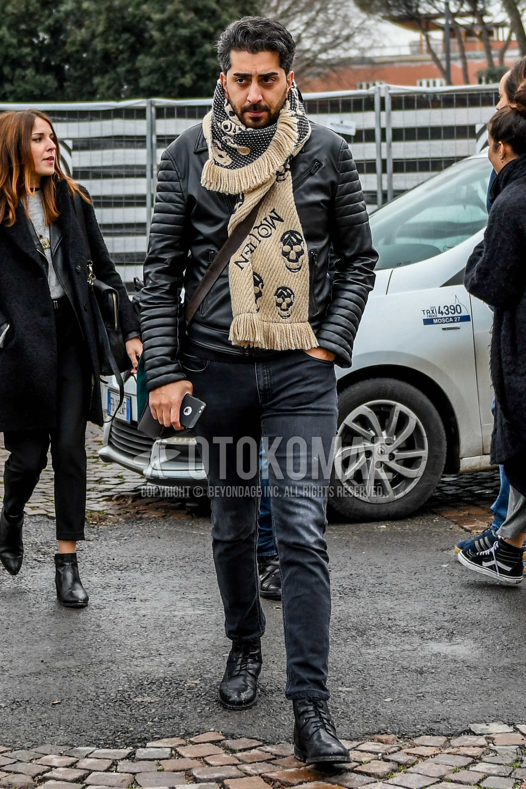 Men's winter outfit with brown graphic scarf, black plain riders jacket, dark gray plain denim/jeans, black  boots.
