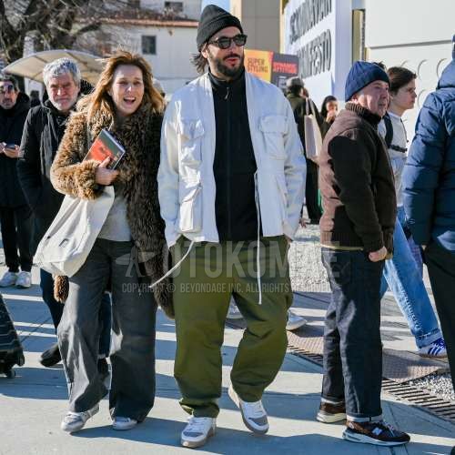 黒無地のニットキャップ、ボストンの黒無地のサングラス、白無地のアウター、黒無地のフリースジャケット、オリーブグリーン無地のチノパン、白ローカットのスニーカーを合わせた冬のメンズコーデ・着こなし。