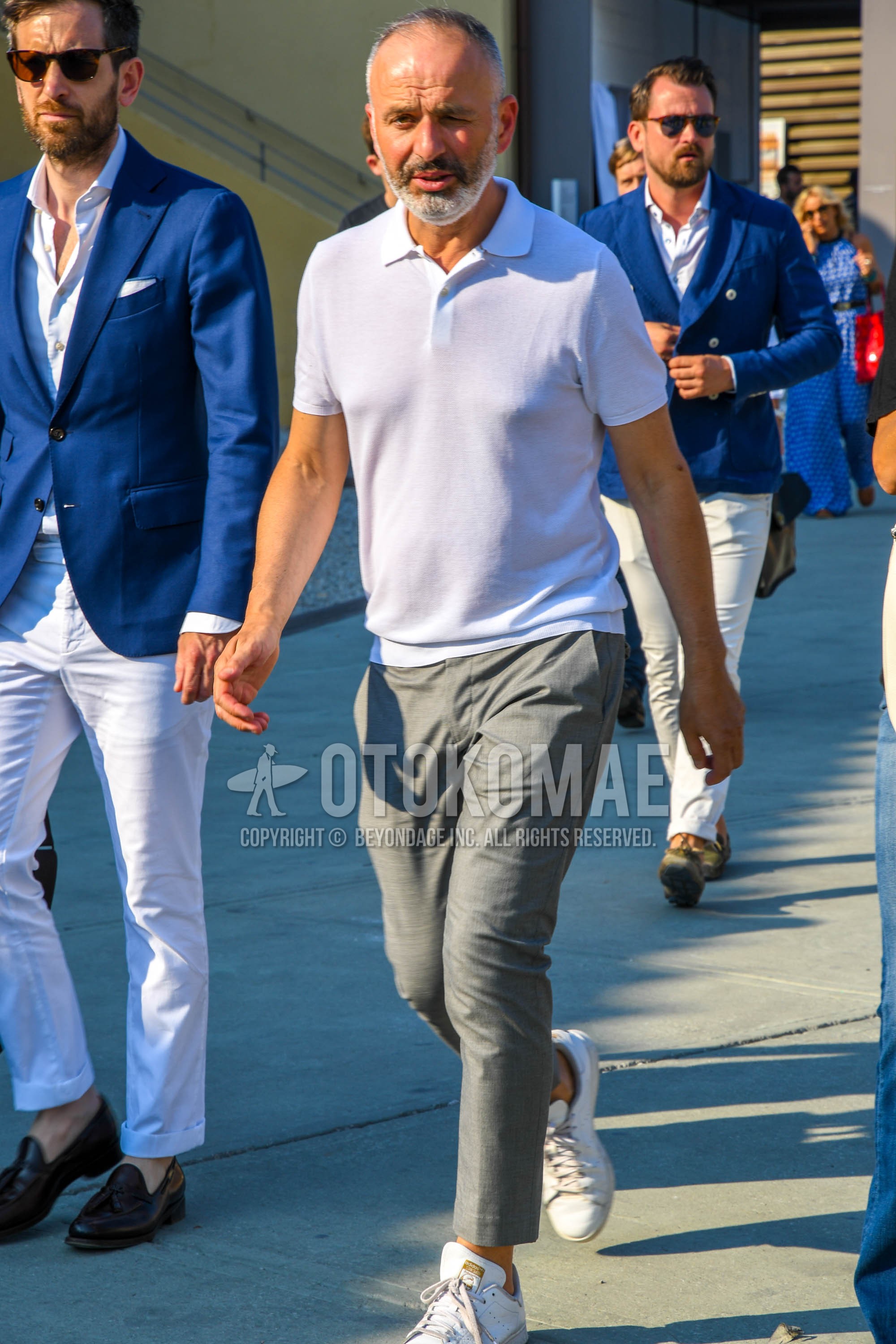 Men's summer outfit with white plain polo shirt, gray plain slacks, plain ankle pants, white low-cut sneakers.