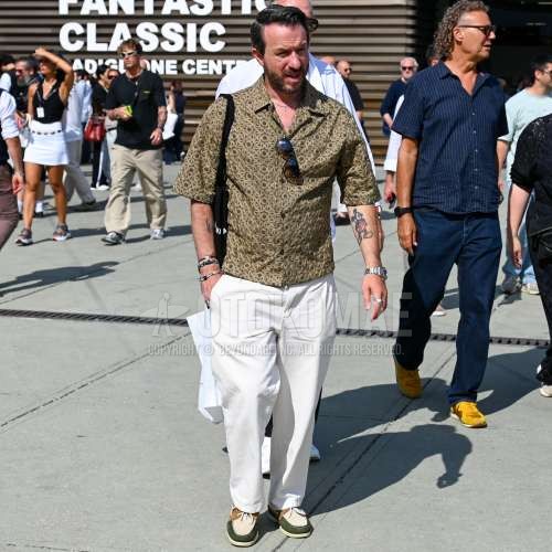 黒無地のサングラス、開襟　オープンカラーのイエロー・ブラウントップス/インナーのシャツ、白無地のスラックス、マルチカラーモカシン/デッキシューズの革靴、黒レタードのトートバッグを合わせた春夏のメンズコーデ・着こなし。