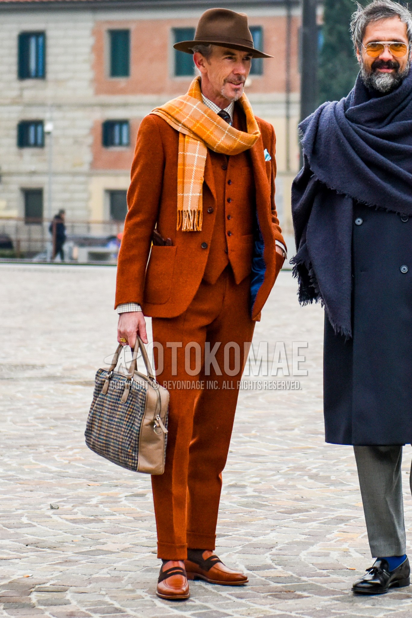 Men's autumn winter outfit with brown plain hat, orange check scarf, orange coin loafers leather shoes, brown check briefcase/handbag, orange plain three-piece suit.