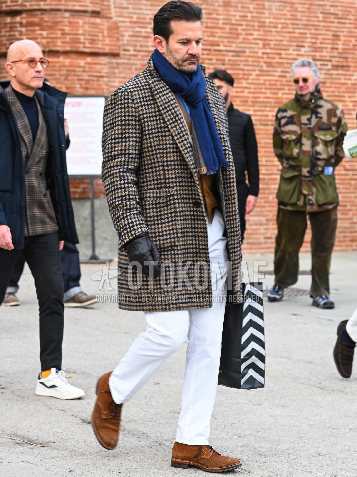 Men's autumn winter outfit with navy plain scarf, beige check chester coat, brown plain casual vest, blue plain denim shirt/chambray shirt, white plain slacks, brown plain toe leather shoes.