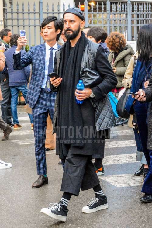 黒無地のニットキャップ、黒無地のマフラー/ストール、黒無地のキルティングジャケット、ダークグレー無地のアウター、ダークグレー無地のワイドパンツ、黒ボーダーのソックス、ダークグレーローカットのスニーカーを合わせた冬のメンズコーデ・着こなし。