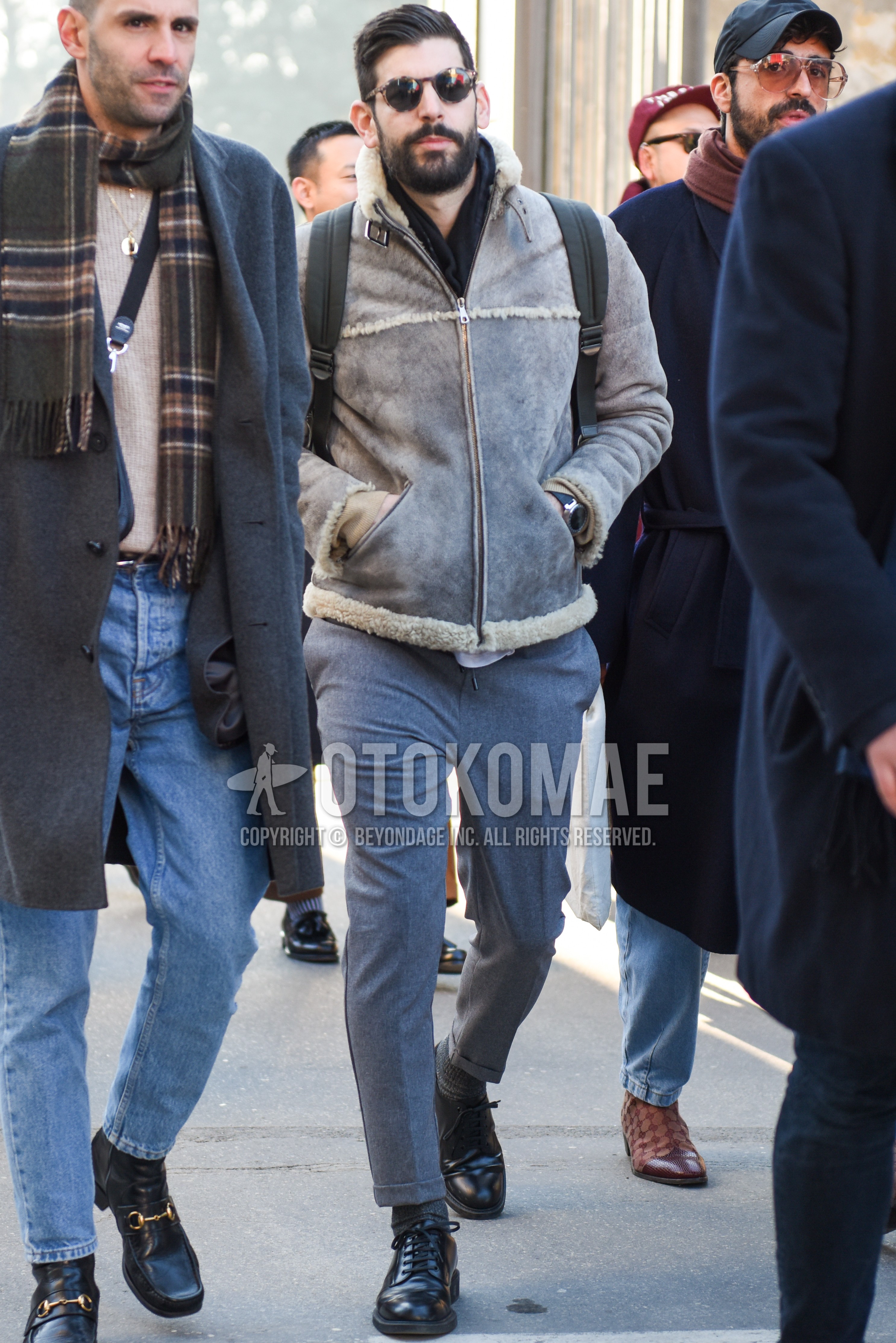 Men's winter outfit with black tortoiseshell sunglasses, dark gray plain scarf, gray plain leather jacket, gray plain slacks, gray plain cropped pants, gray plain socks, black plain toe leather shoes.