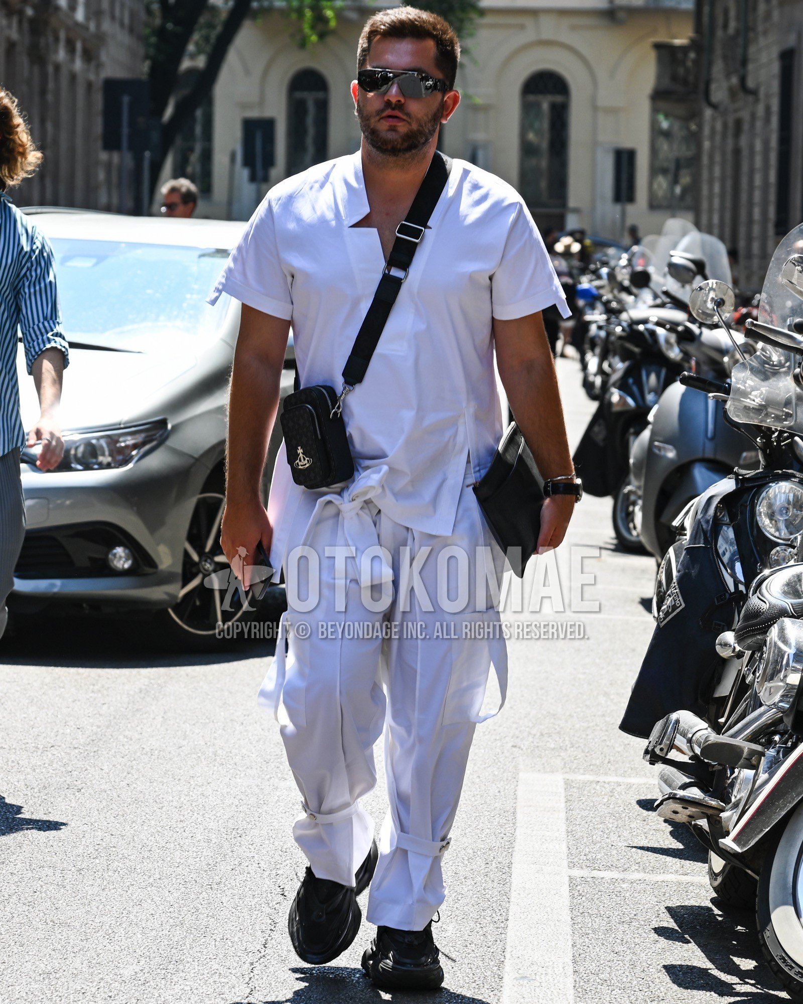 Men's summer outfit with silver plain sunglasses, white plain shirt, white plain cargo pants, black low-cut sneakers, black plain shoulder bag.