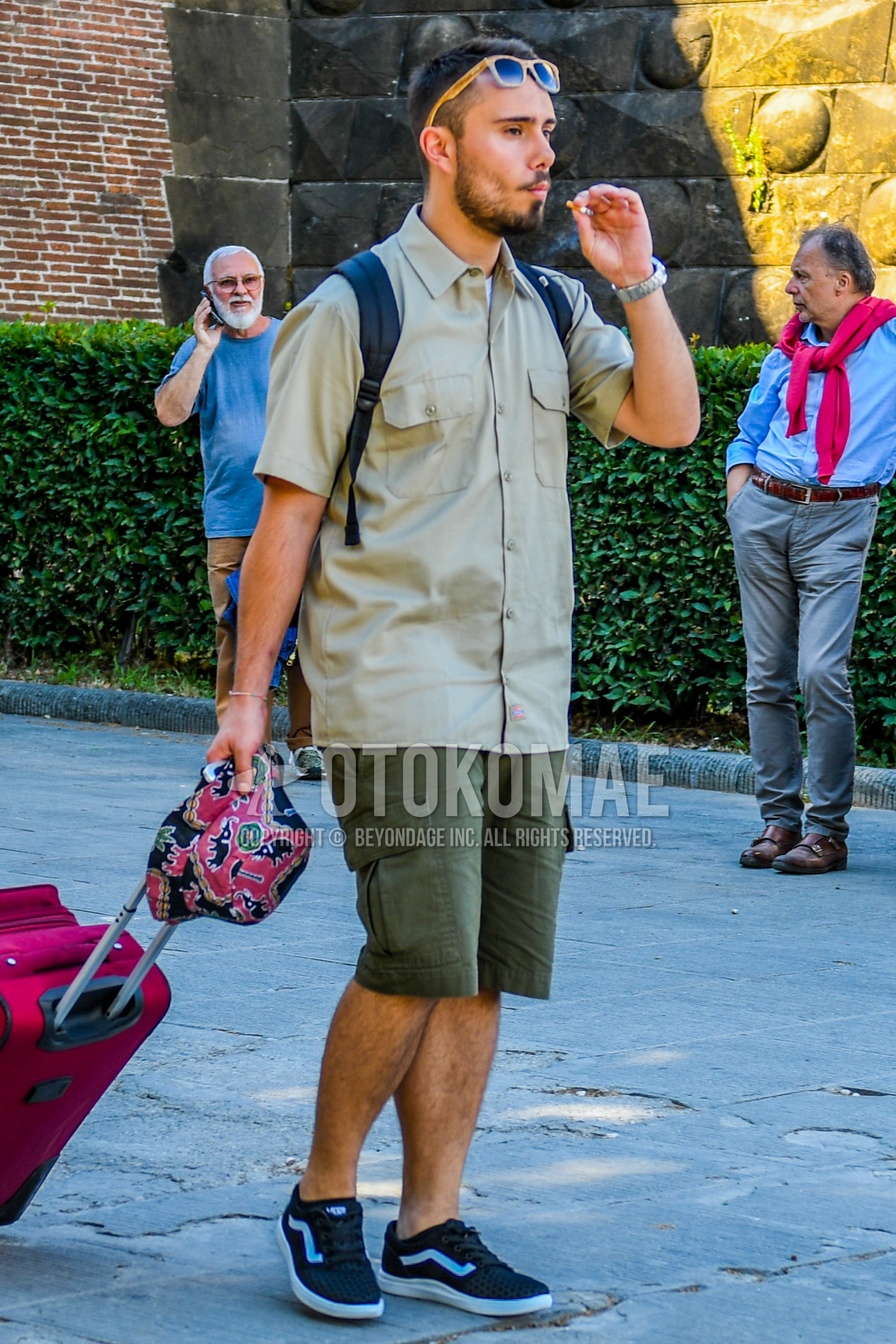 Men's summer outfit with plain sunglasses, beige plain shirt, olive green plain cargo pants, black low-cut sneakers.