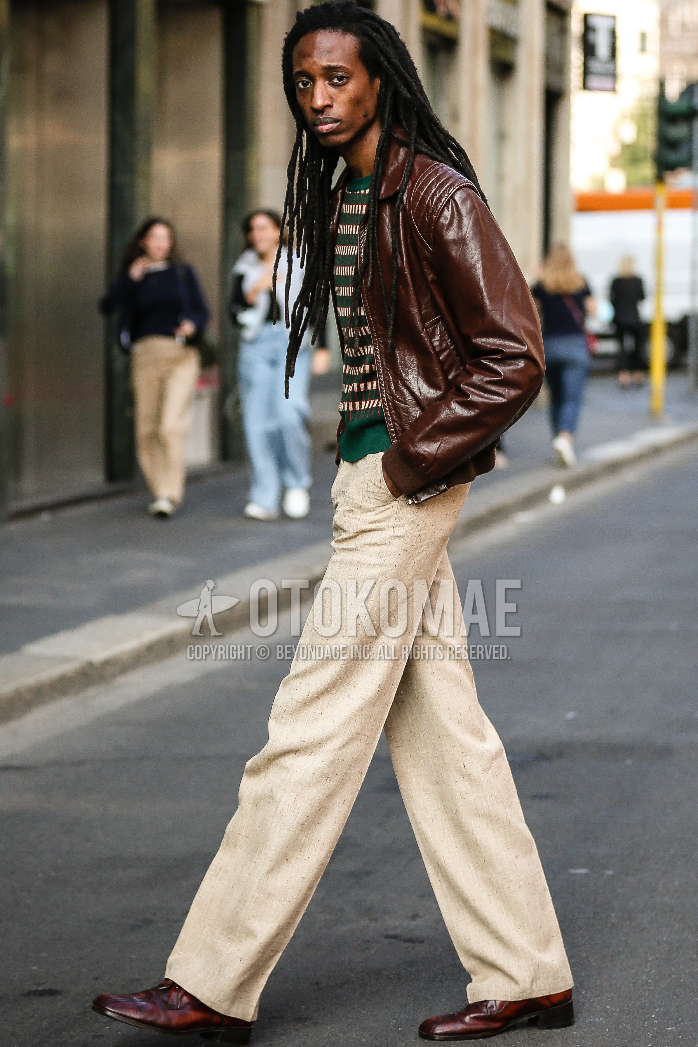 Men's spring summer outfit with brown plain leather jacket, green horizontal stripes sweater, beige plain slacks, red  leather shoes.