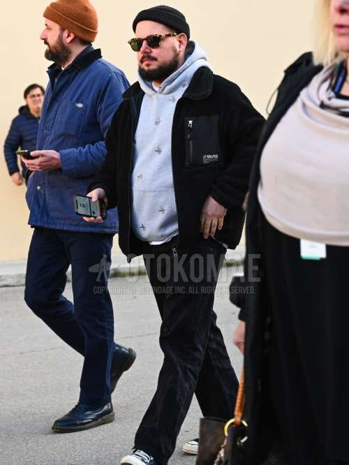 黒無地のニットキャップ、ブラウンべっ甲のサングラス、黒無地のフリースジャケット、グレートップス/インナーのフーディ、黒無地のデニム/ジーンズ、黒ローカットのスニーカーを合わせた秋冬のメンズコーデ・着こなし。