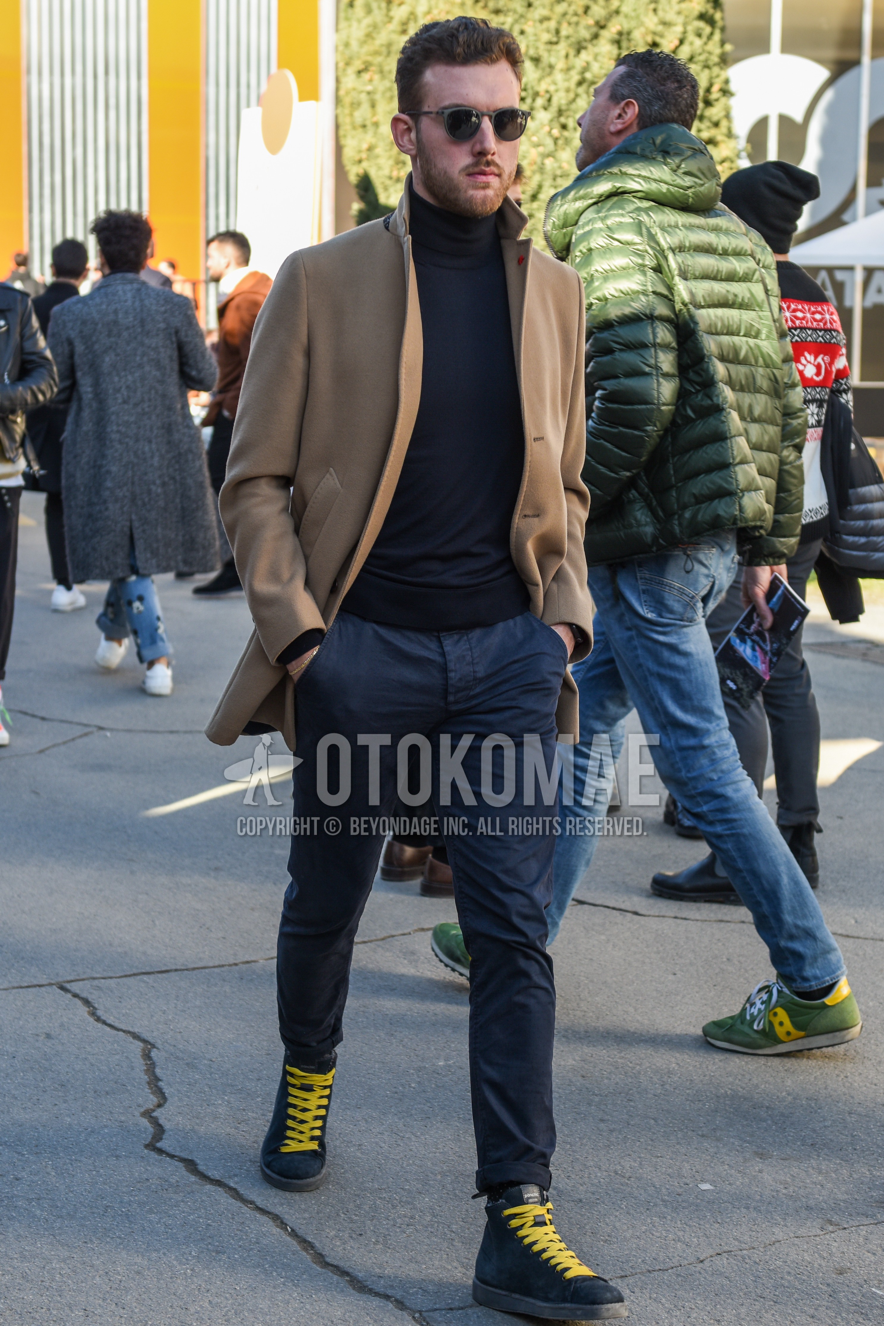 Men's autumn winter outfit with gray plain sunglasses, beige plain chester coat, dark gray plain turtleneck knit, navy plain chinos, black high-cut sneakers.