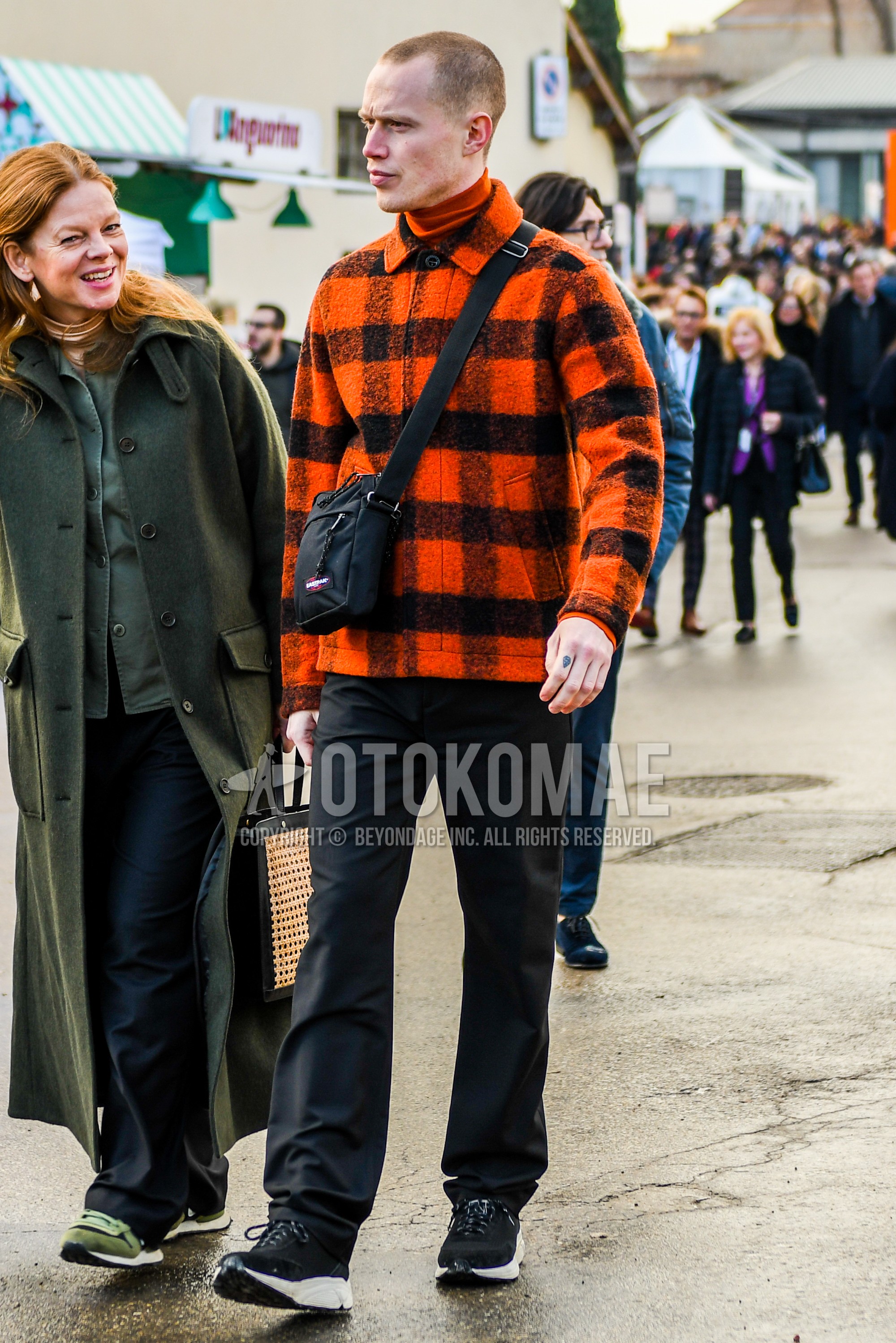 Men's autumn winter outfit with orange check shirt jacket, red plain turtleneck knit, black plain slacks, black low-cut sneakers, black plain succoshe.