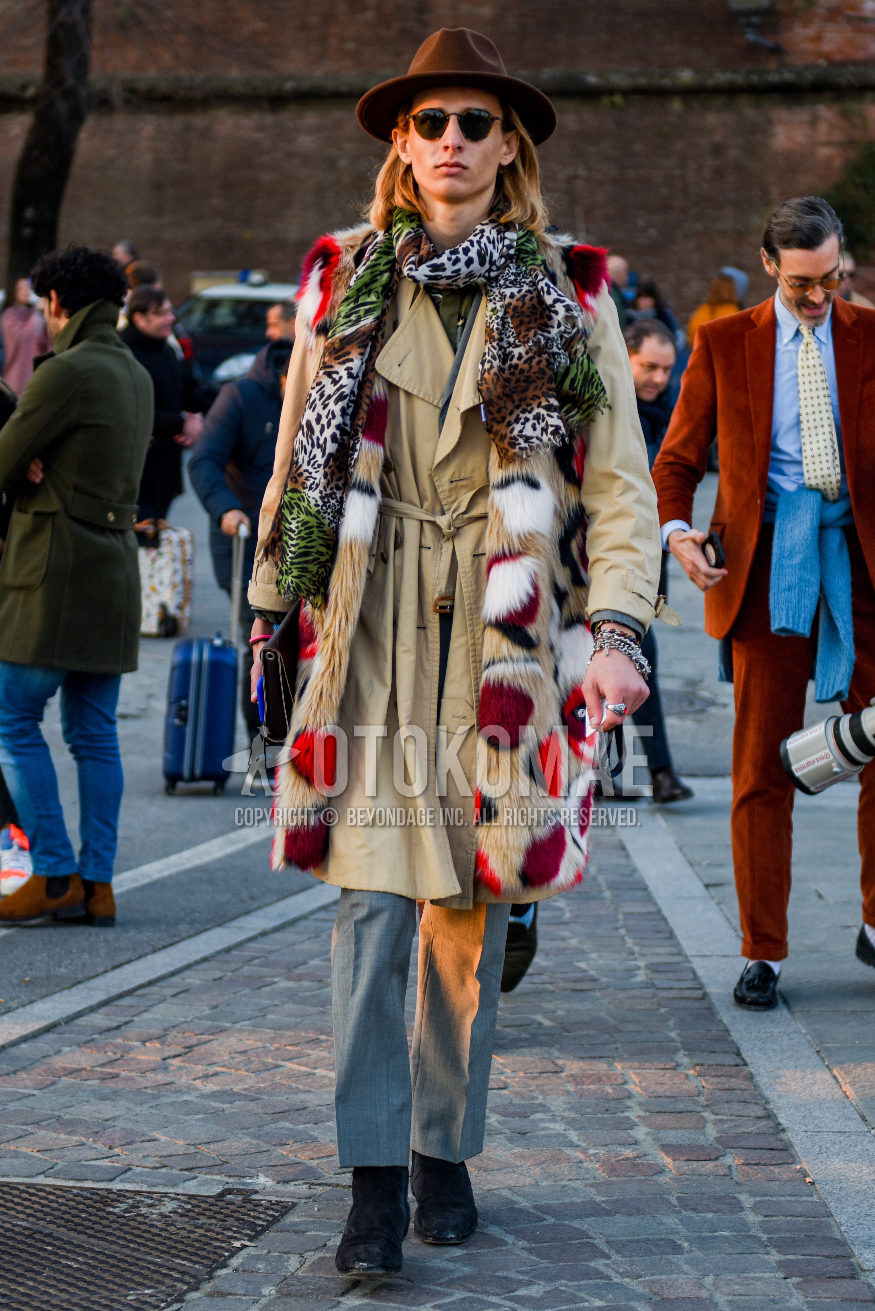 Men's autumn winter outfit with brown plain hat, brown tortoiseshell sunglasses, multi-color scarf scarf, beige plain trench coat, gray plain slacks, gray plain ankle pants, black side-gore boots.