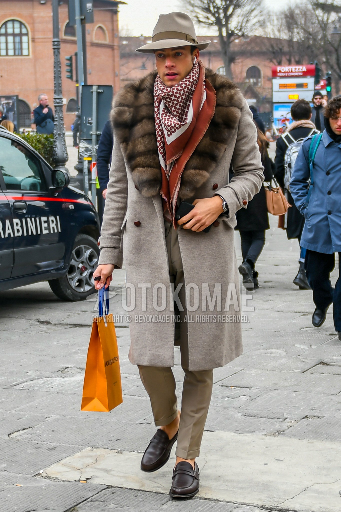 Men's autumn winter outfit with beige plain hat, white brown scarf scarf, beige plain shawl collar coat, beige plain slacks, brown coin loafers leather shoes.