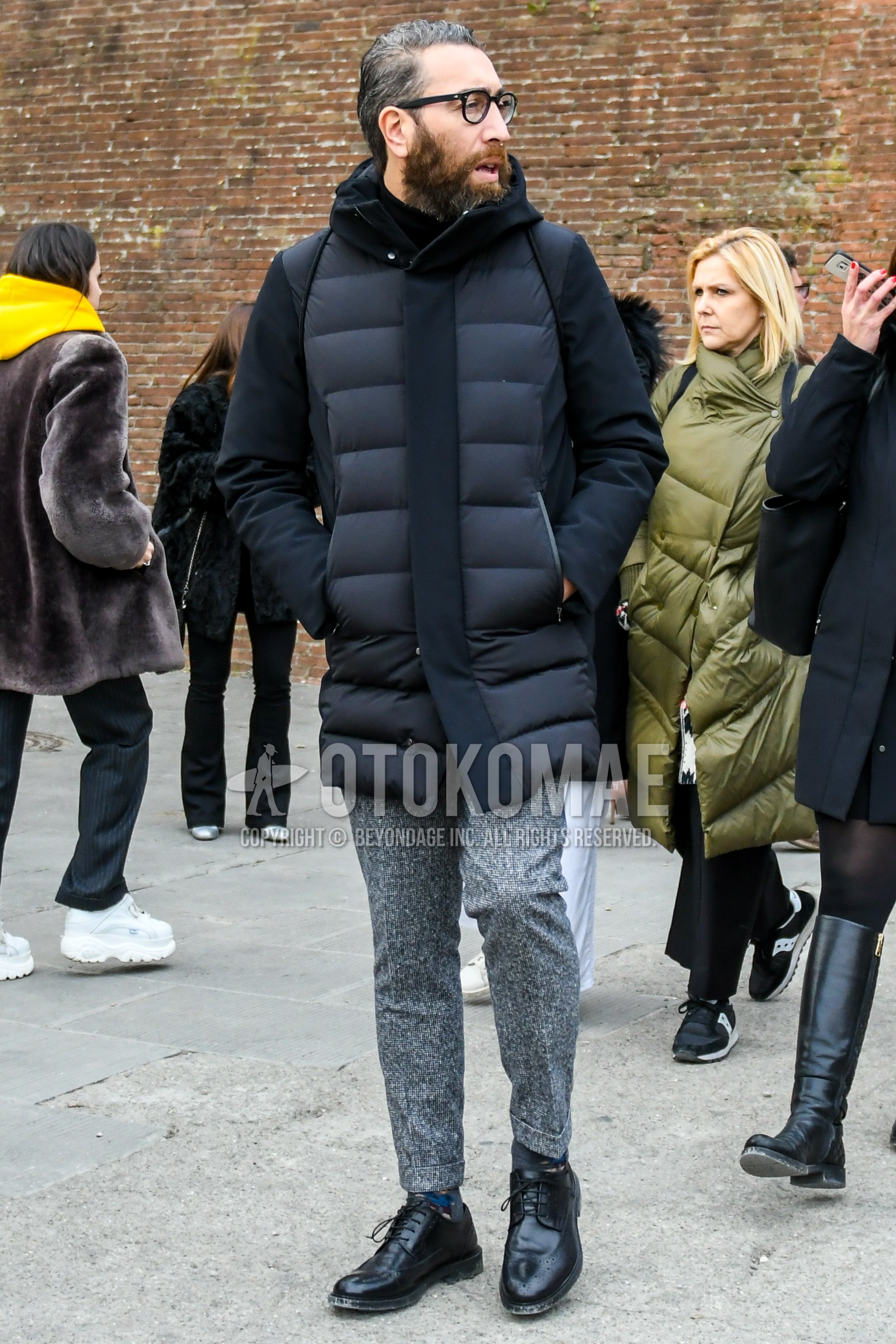 Men's winter outfit with plain glasses, black plain down jacket, gray plain slacks, black wing-tip shoes leather shoes.