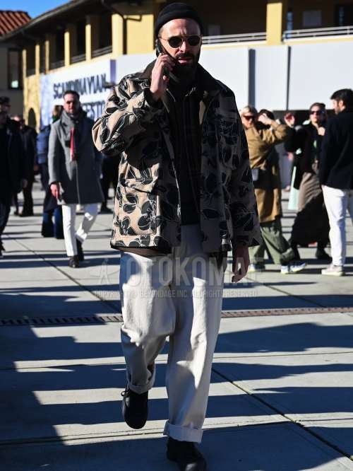 黒無地のニットキャップ、黒・ゴールド無地のサングラス、ベージュ・黒グラフィックのミリタリージャケット(MA-1、M-65以外)、黒無地のタートルネックニット、オリーブグリーンチェックのシャツ、白無地のチノパン、オリーブグリーンローカットのスニーカーを合わせた秋冬のメンズコーデ・着こなし。