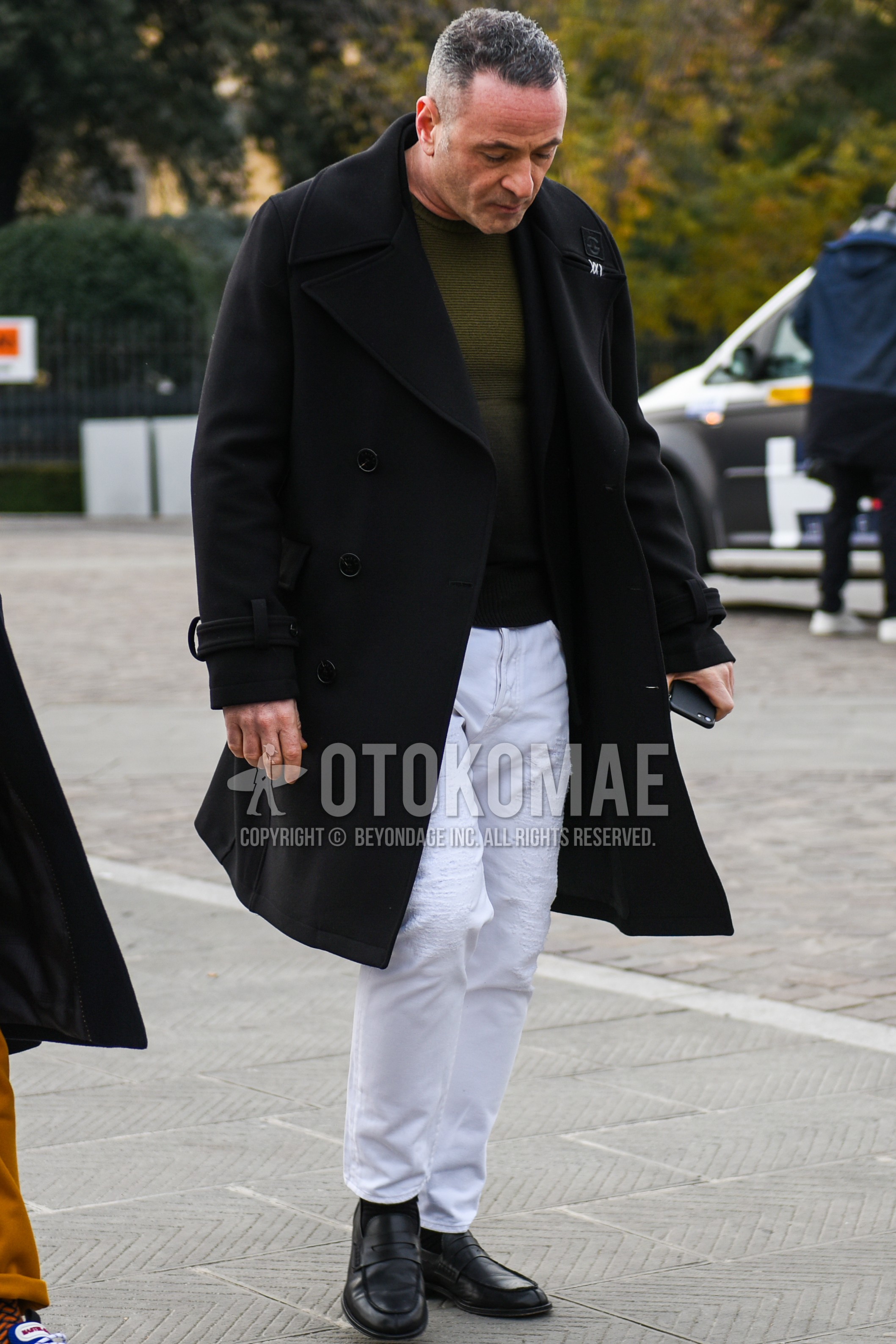 Men's autumn winter outfit with black plain chester coat, olive green plain sweater, white plain cotton pants, white plain cropped pants, black plain socks, black coin loafers leather shoes.