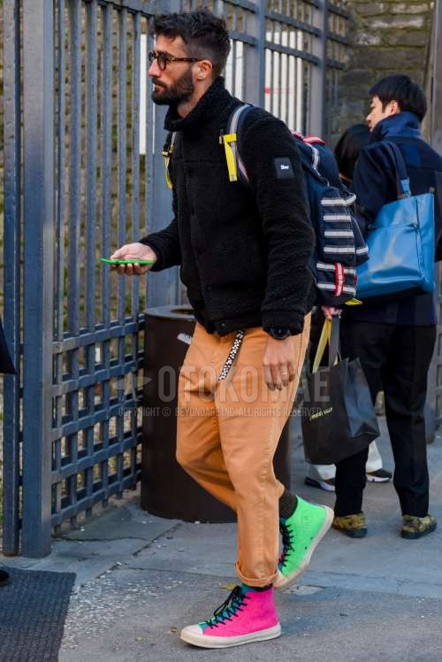 ブラウンべっ甲のメガネ、黒無地のフリースジャケット、ベージュ無地のコットンパンツ、コンバース オールスターのマルチカラーハイカットのスニーカーを合わせた秋冬のメンズコーデ・着こなし。