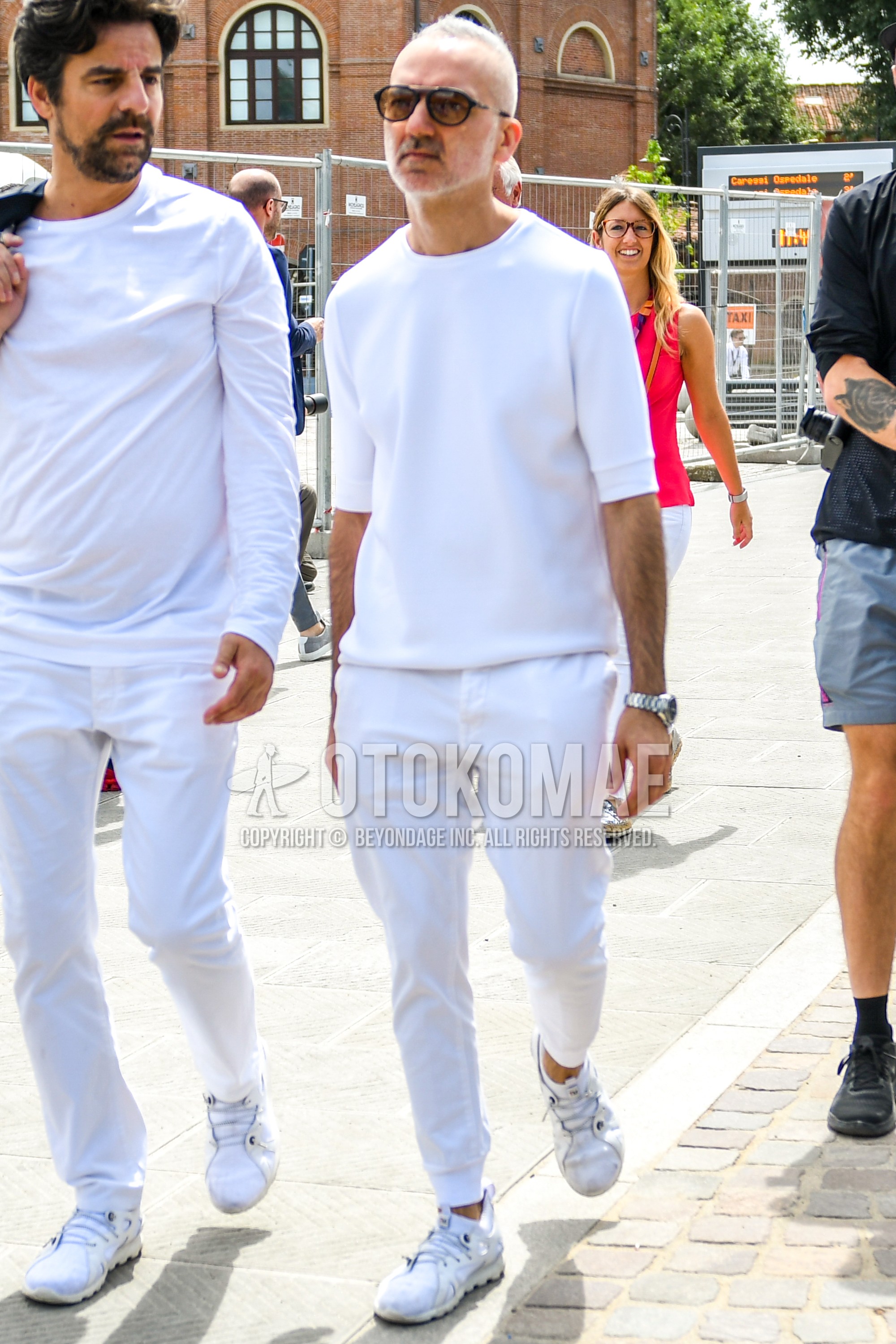 Men's spring summer outfit with black plain sunglasses, white plain t-shirt, white plain jogger pants/ribbed pants, white sneakers.