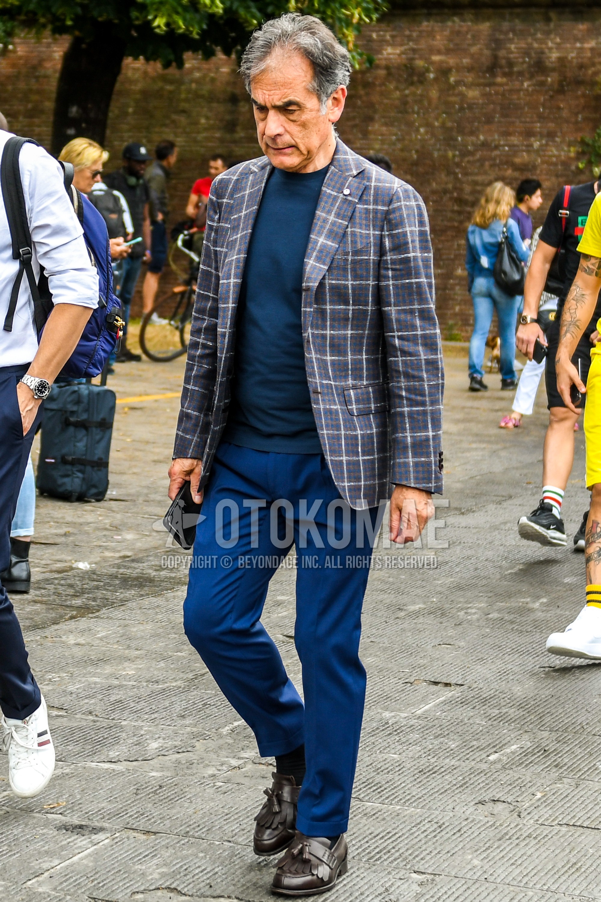 Men's spring summer autumn outfit with gray check tailored jacket, navy plain t-shirt, blue plain slacks, navy plain socks, brown tassel loafers leather shoes.