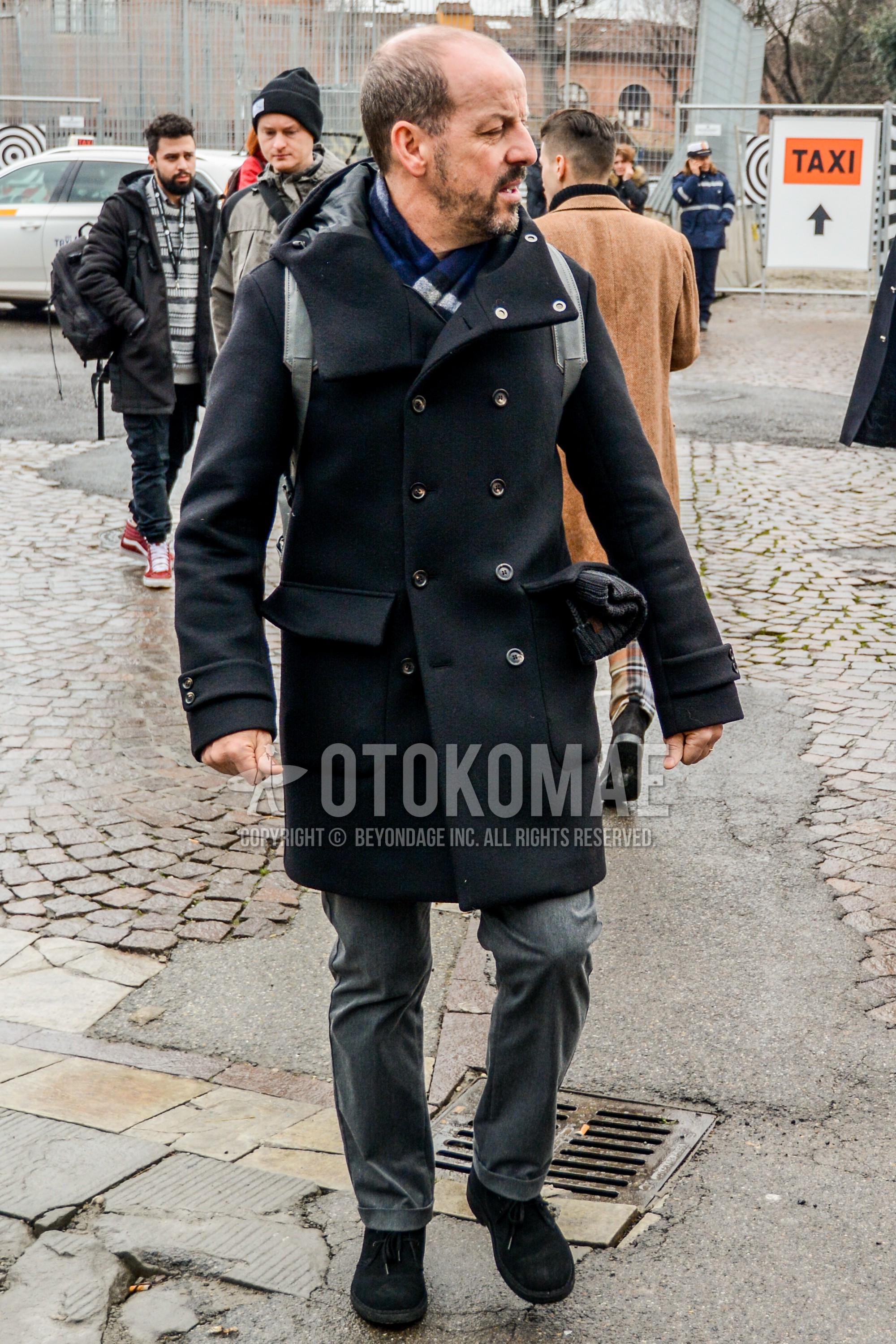 Men's winter outfit with navy plain scarf, black plain hooded coat, gray plain slacks, black suede shoes leather shoes.