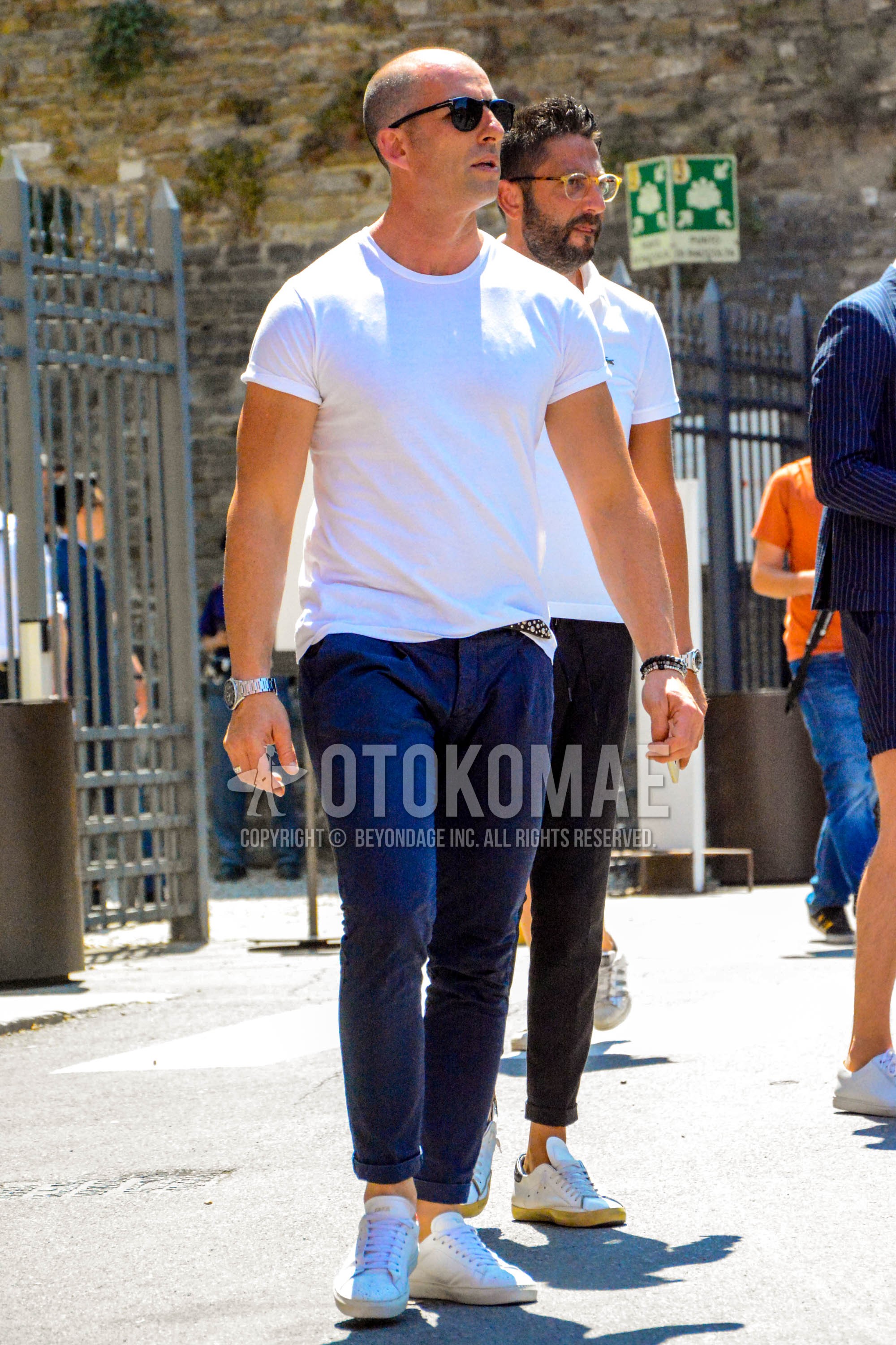 Men's summer outfit with plain sunglasses, white plain t-shirt, navy plain chinos, white sneakers.