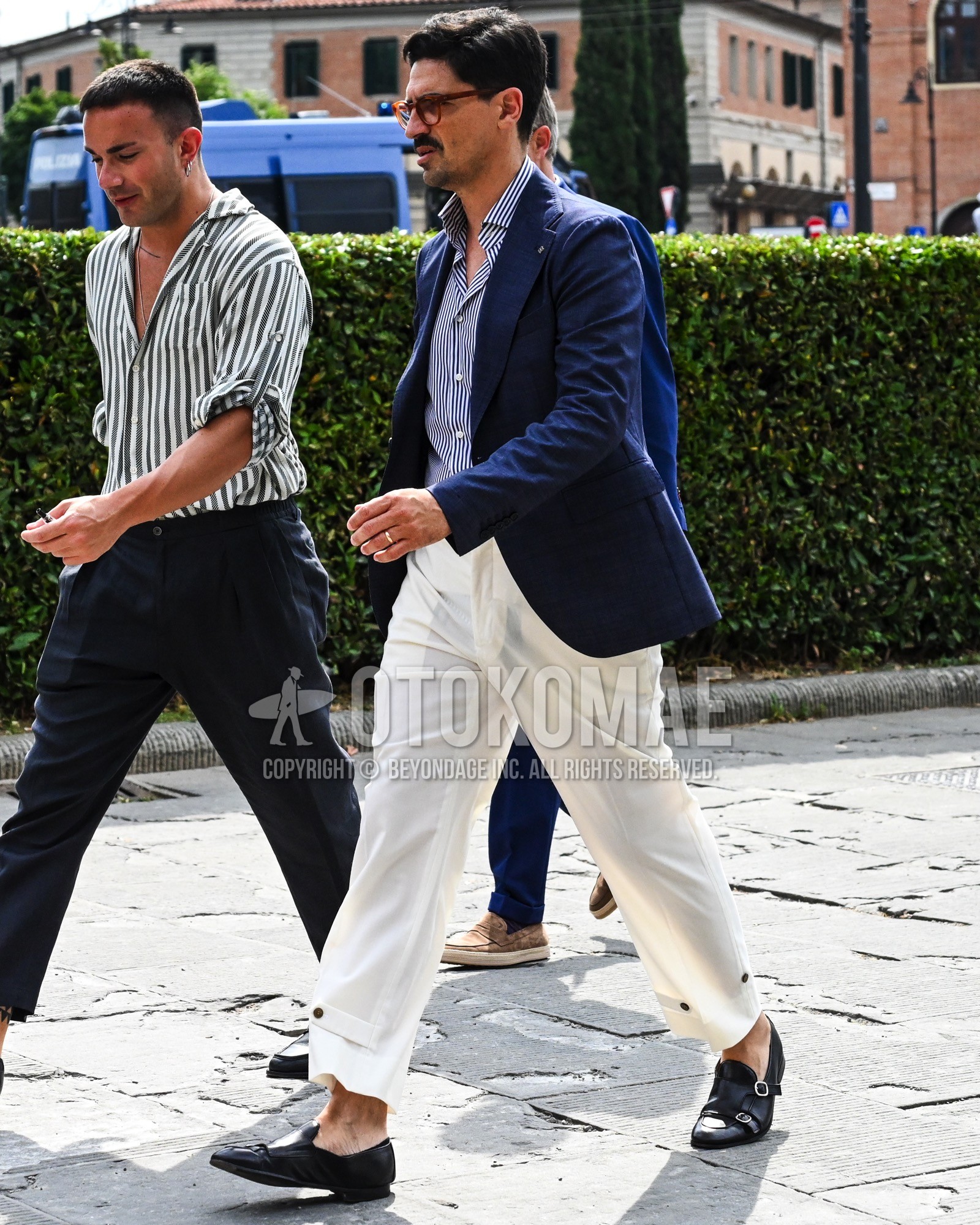 Men's spring summer autumn outfit with clear tortoiseshell sunglasses, navy plain tailored jacket, blue stripes shirt, white plain cargo pants, black  loafers leather shoes.