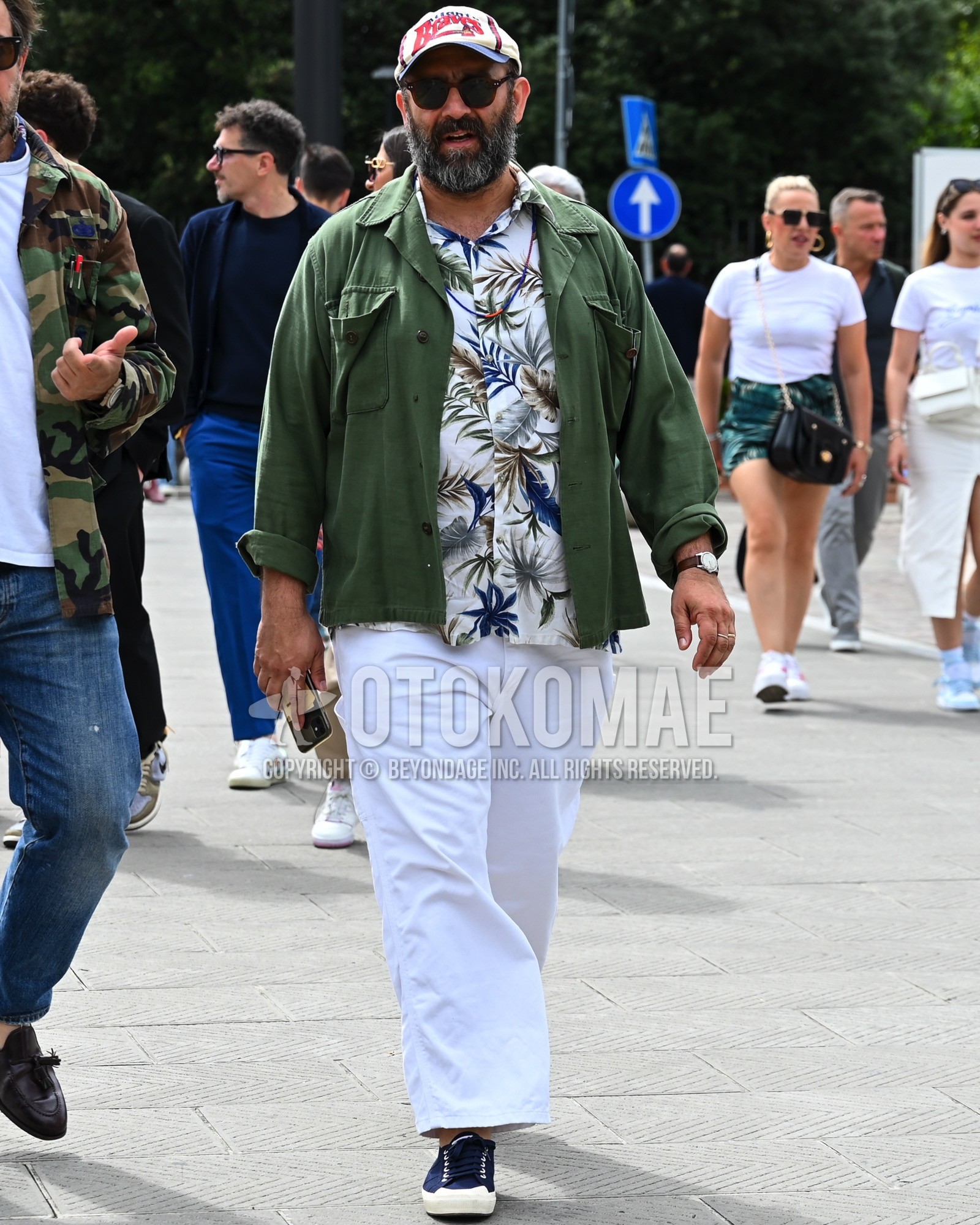 Men's spring summer autumn outfit with white deca logo baseball cap, black plain sunglasses, olive green plain military jacket, white whole pattern shirt, white plain wide pants, white plain chinos, navy low-cut sneakers.