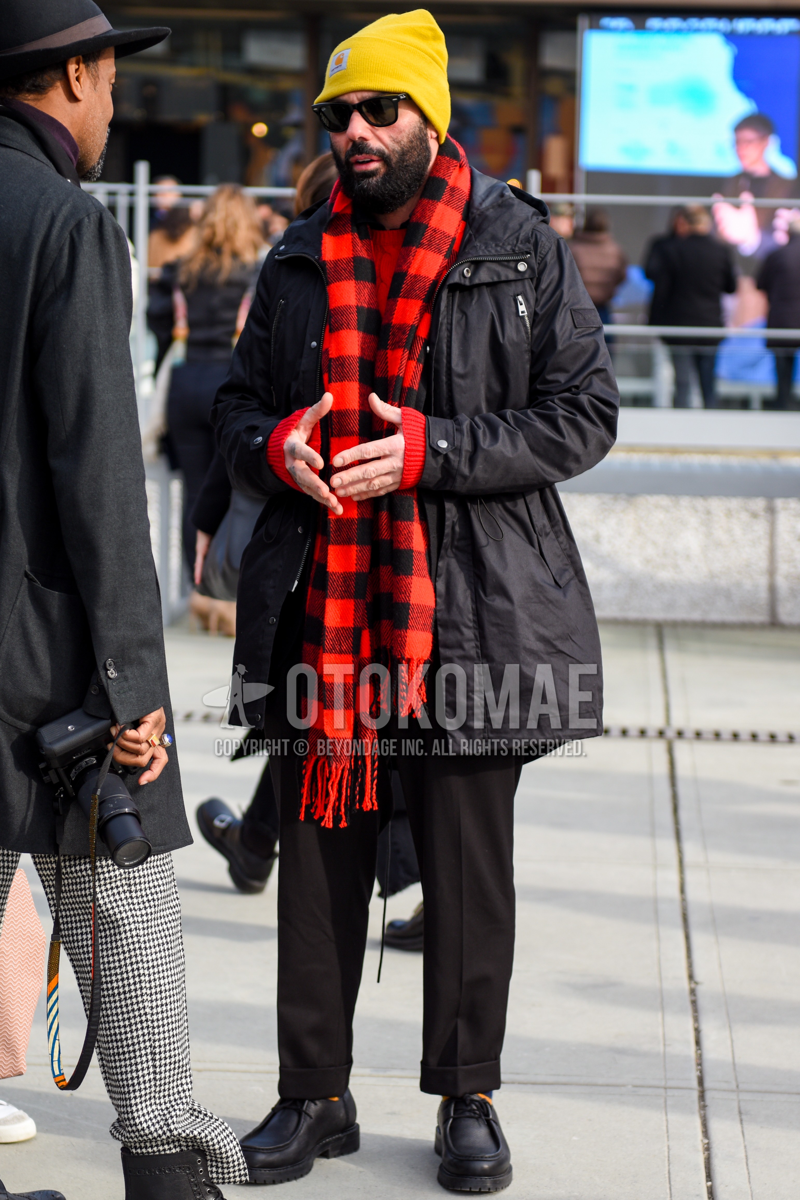 Men's autumn winter outfit with yellow plain knit cap, black plain sunglasses, black red check scarf, black plain hooded coat, black plain slacks, black  leather shoes.