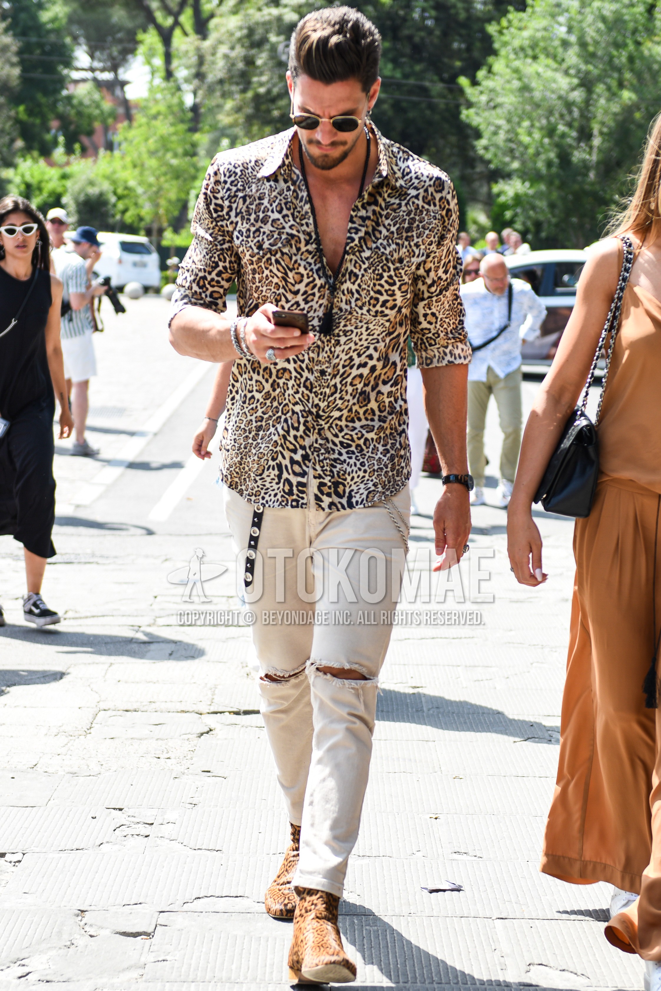 Men's summer outfit with gold black plain sunglasses, yellow black leopard shirt, white plain damaged jeans, yellow brown  boots.