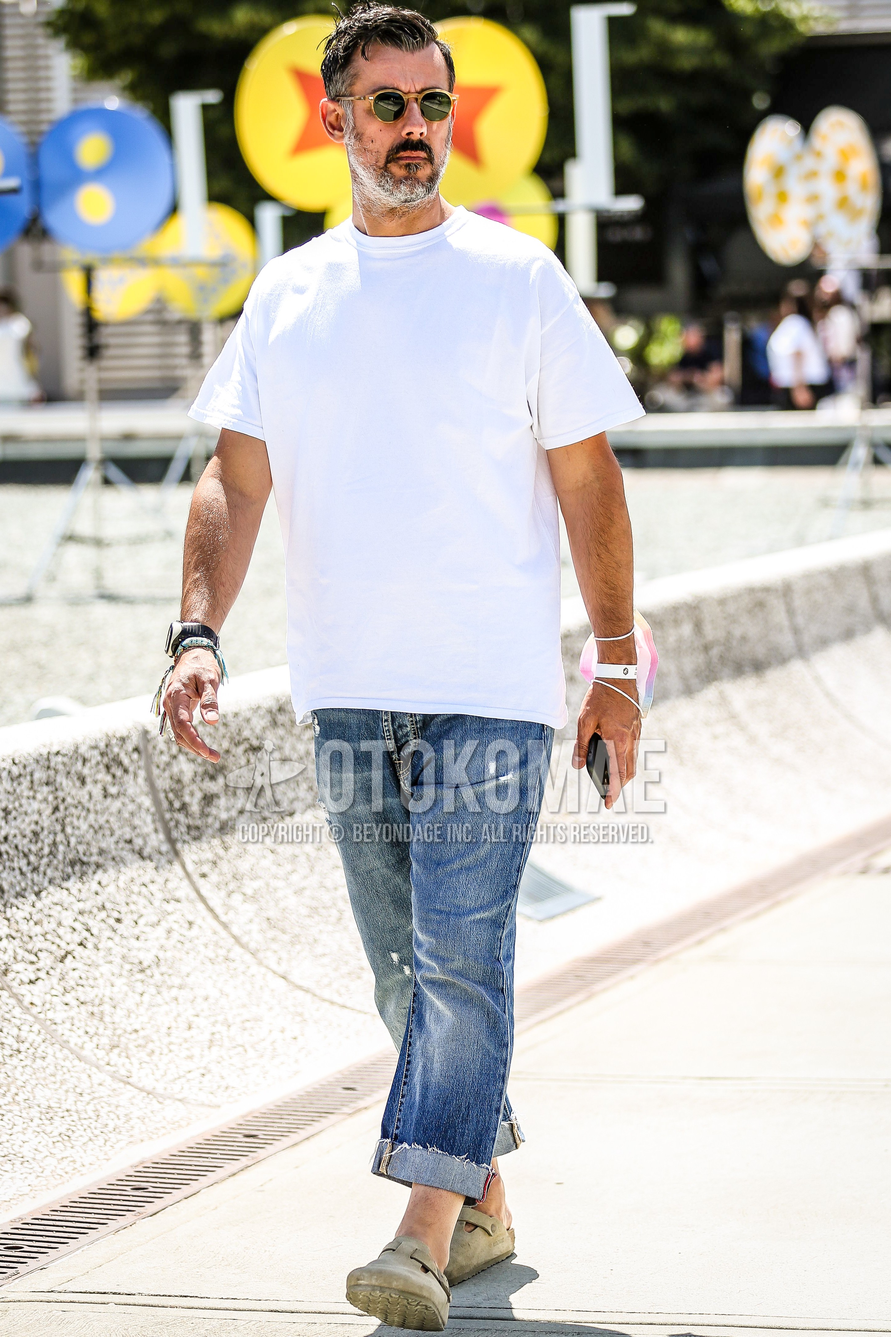 Men's summer outfit with brown tortoiseshell sunglasses, white plain t-shirt, blue plain denim/jeans, beige sandals.