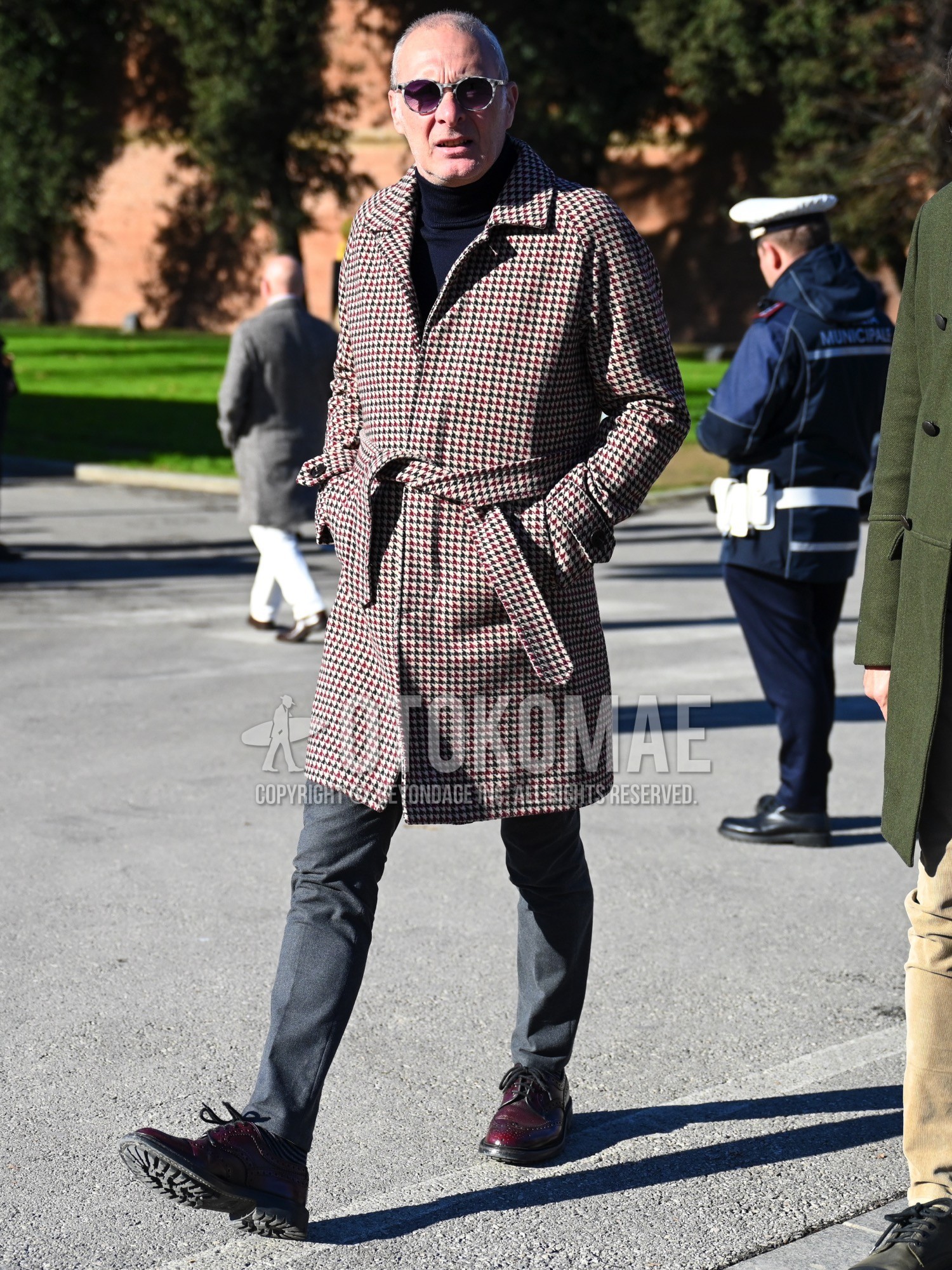 Men's autumn winter outfit with silver purple plain sunglasses, beige red black check belted coat, navy plain turtleneck knit, gray plain slacks, red brogue shoes leather shoes.