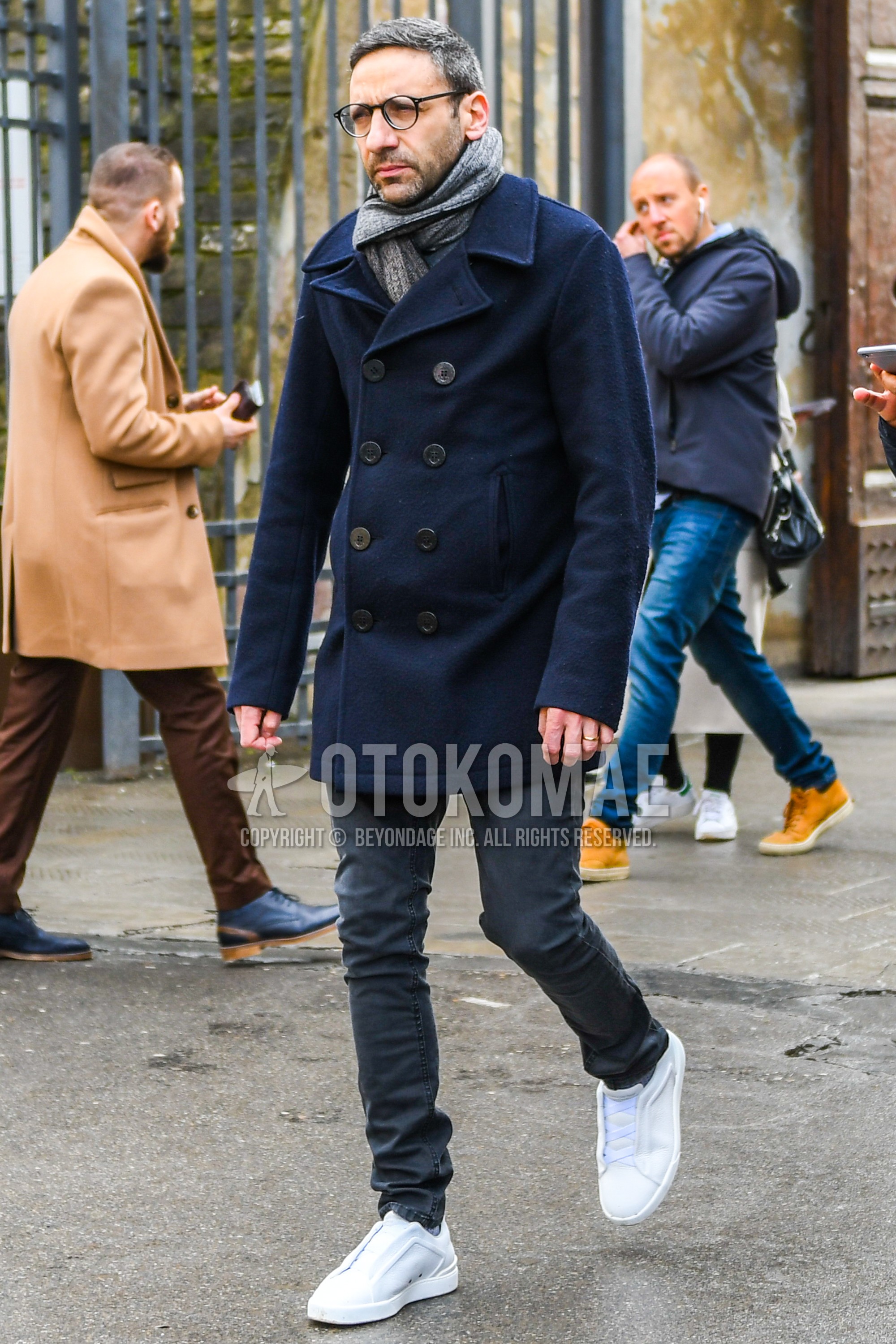 Men's winter outfit with plain glasses, gray plain scarf, navy plain p coat, dark gray plain chinos, white low-cut sneakers.