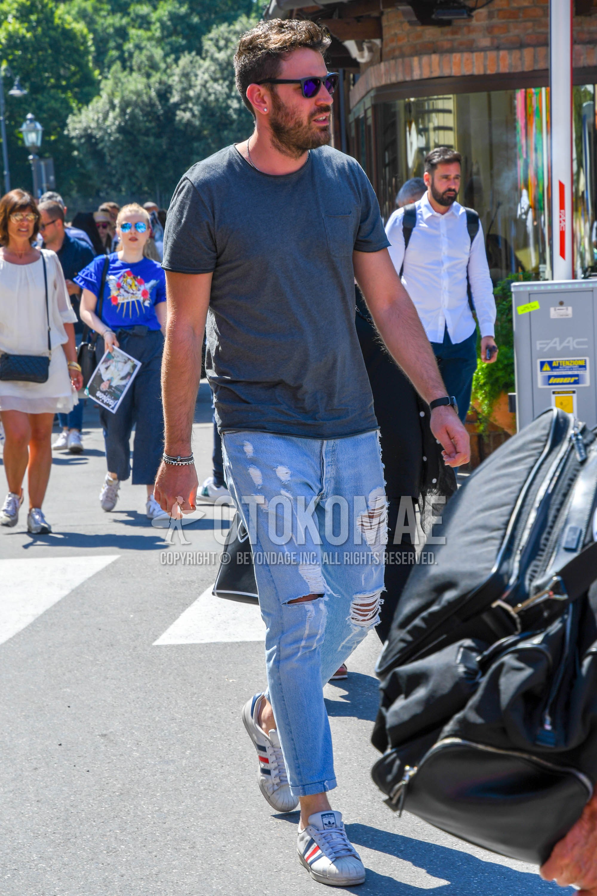 Men's summer outfit with plain sunglasses, gray plain t-shirt, light blue plain damaged jeans, white low-cut sneakers.