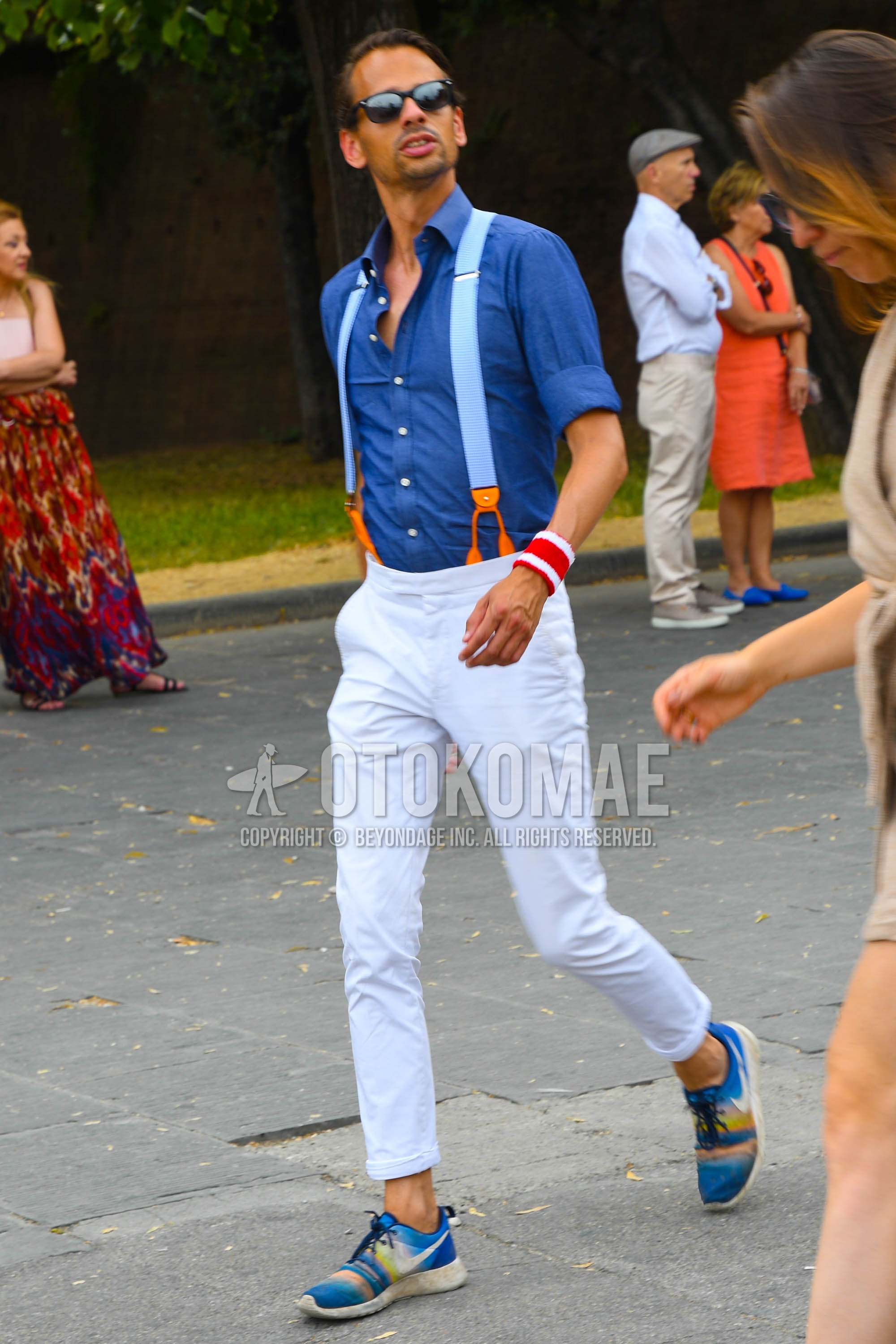 Men's spring summer autumn outfit with plain sunglasses, blue plain shirt, light blue plain suspenders, white plain cotton pants, white plain ankle pants, blue low-cut sneakers.