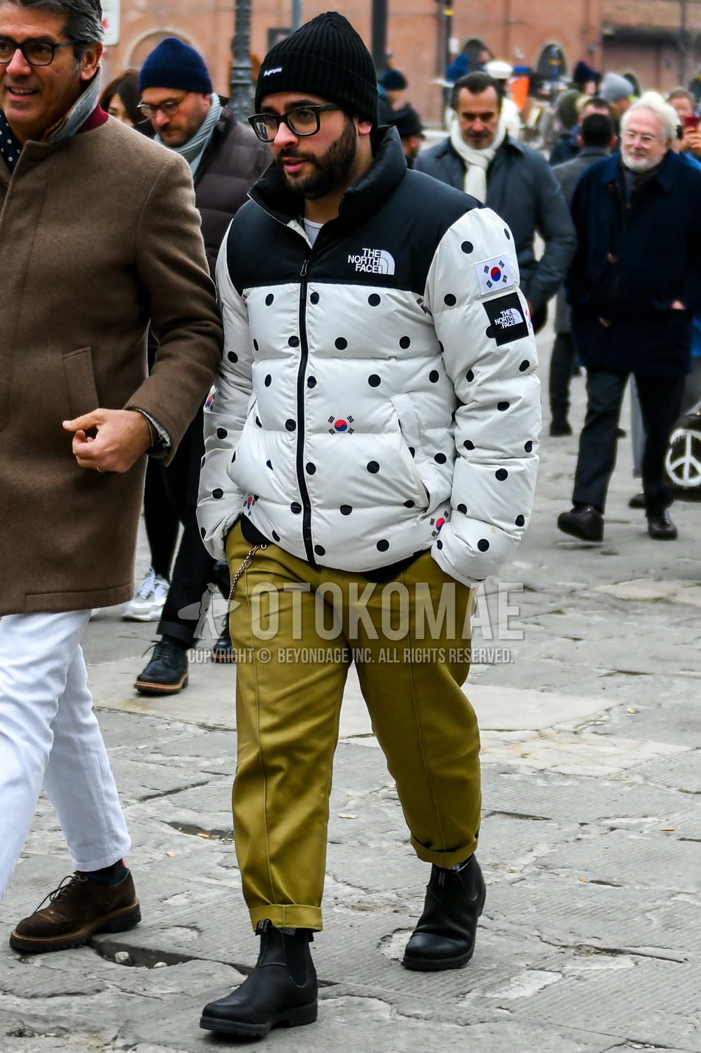 Men's winter outfit with black plain knit cap, white plain down jacket, olive green plain chinos, black side-gore boots.