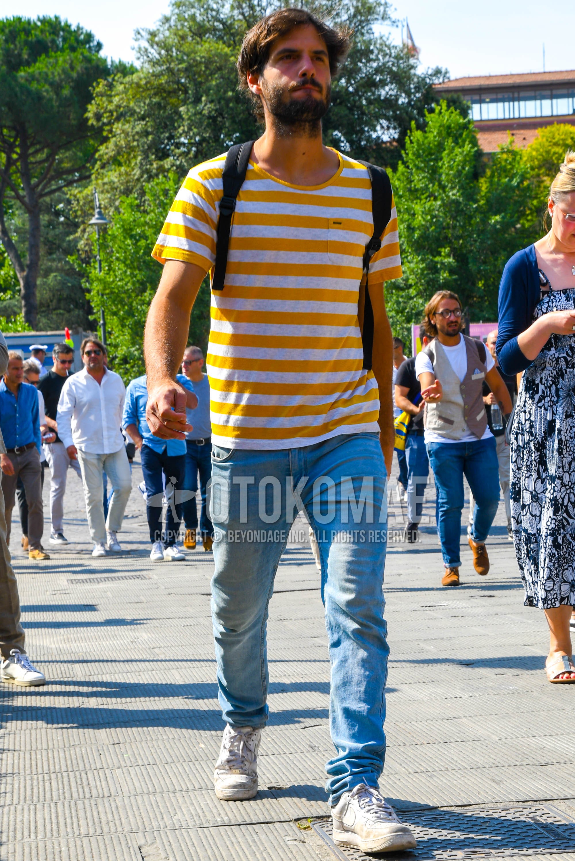 Men's spring summer outfit with white yellow horizontal stripes t-shirt, blue plain denim/jeans, white low-cut sneakers.
