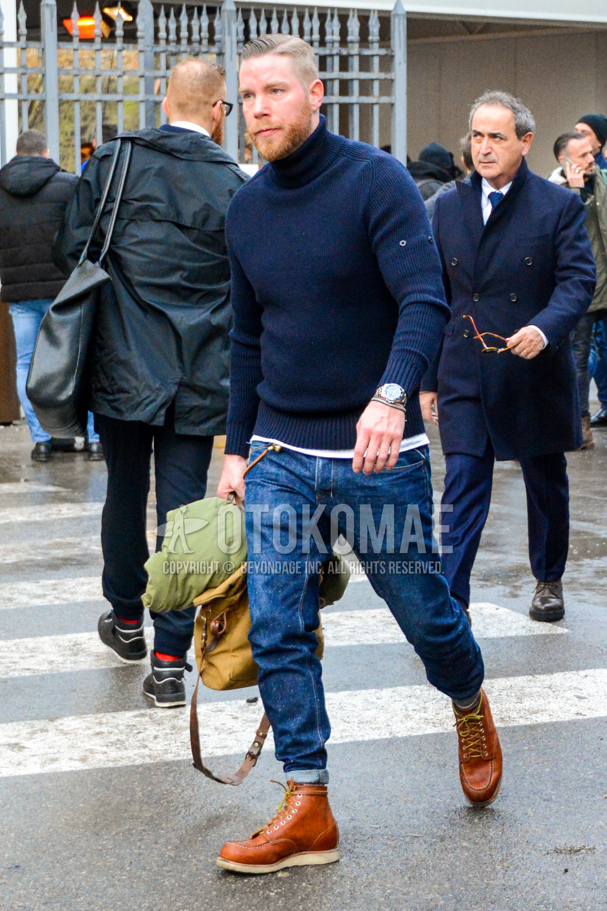 Men's winter outfit with navy plain turtleneck knit, blue plain denim/jeans, brown work boots.