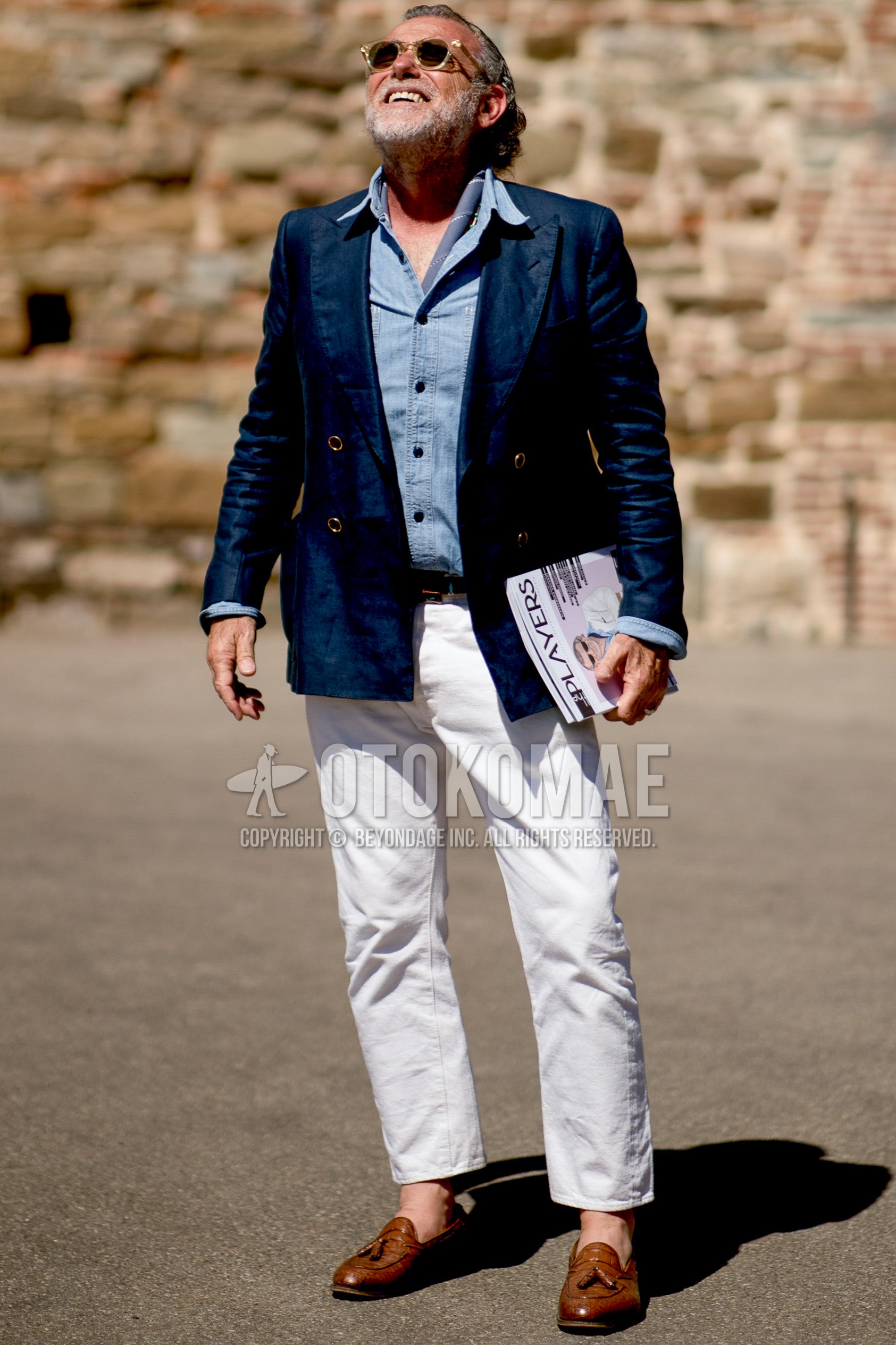 Men's spring summer outfit with clear plain sunglasses, light blue stripes scarf, navy plain tailored jacket, light blue plain denim shirt/chambray shirt, brown plain leather belt, white plain ankle pants, brown tassel loafers leather shoes.