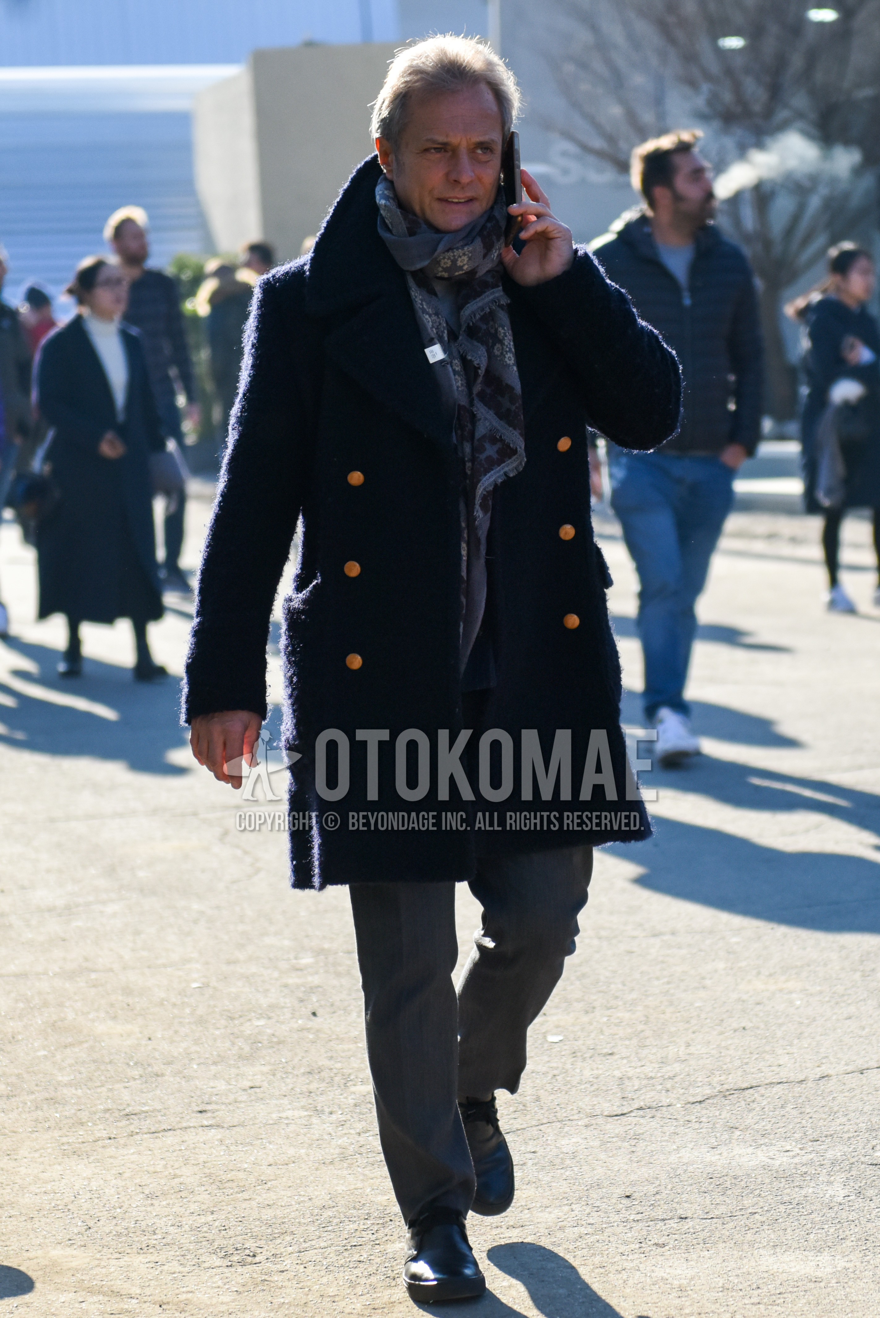 Men's winter outfit with gray scarf scarf, navy plain ulster coat, gray plain slacks, black chukka boots.