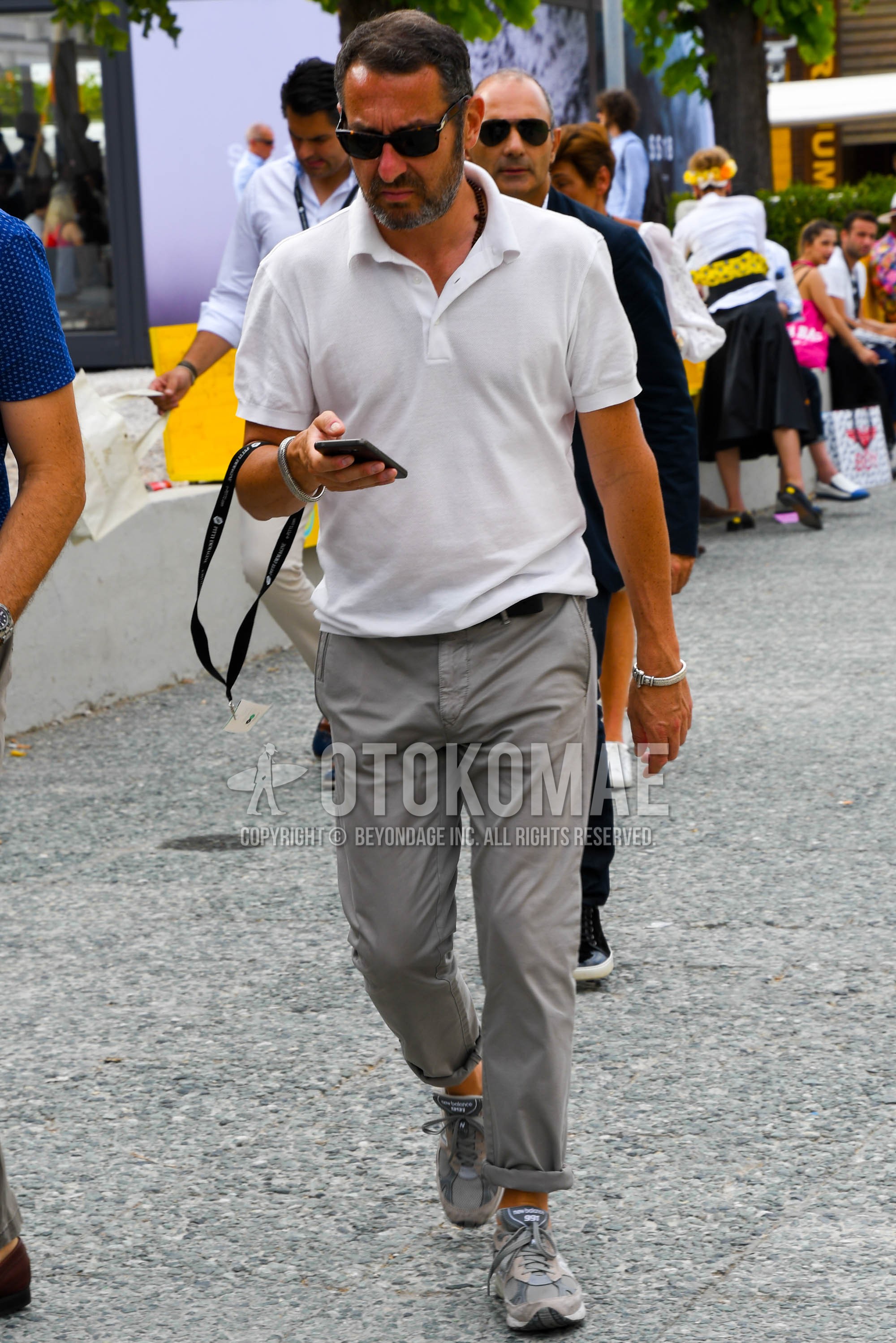 Men's summer outfit with plain sunglasses, white plain polo shirt, gray plain cotton pants, gray low-cut sneakers.