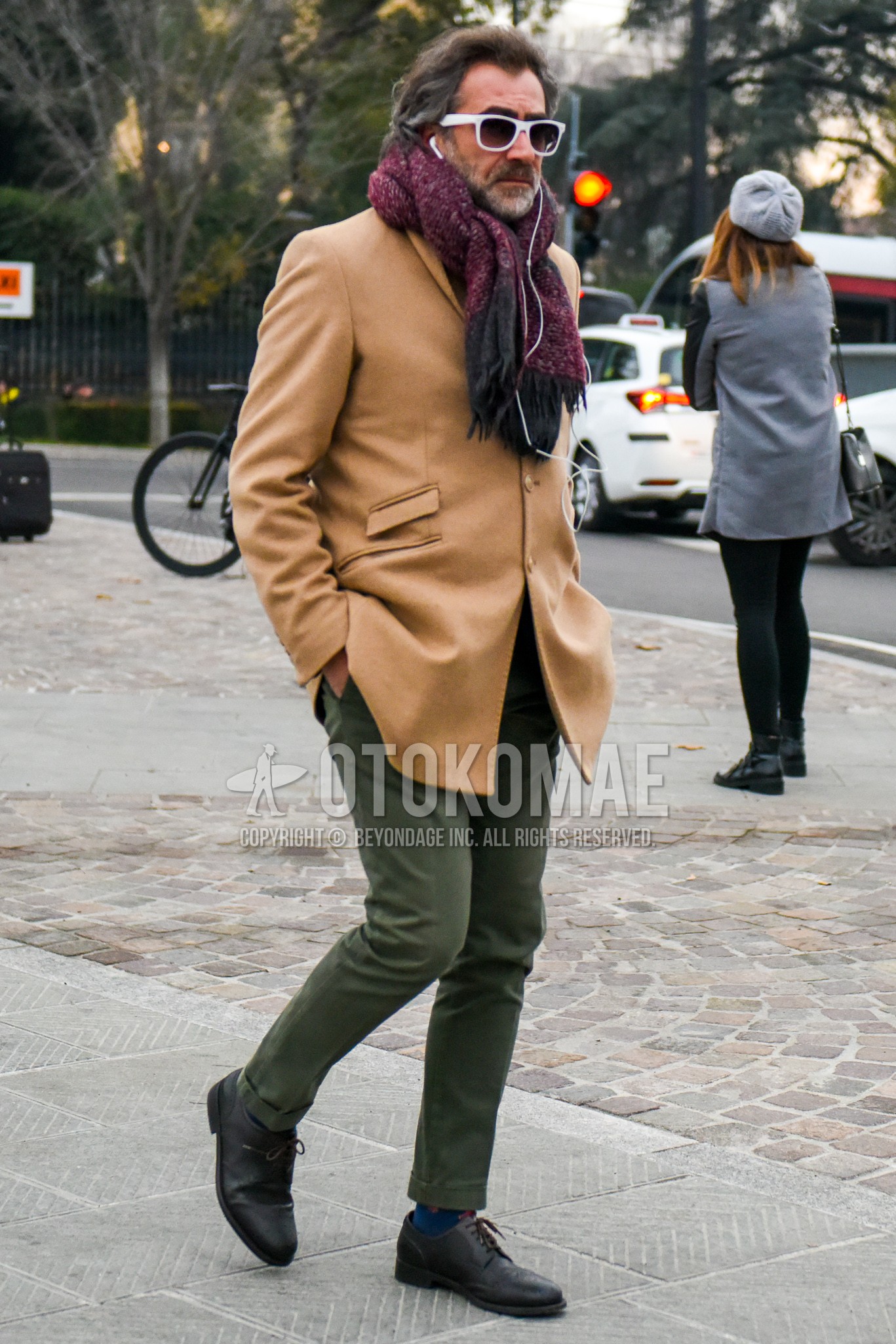 Men's winter outfit with white plain sunglasses, purple scarf scarf, beige plain chester coat, olive green plain chinos, blue socks socks, black wing-tip shoes leather shoes.