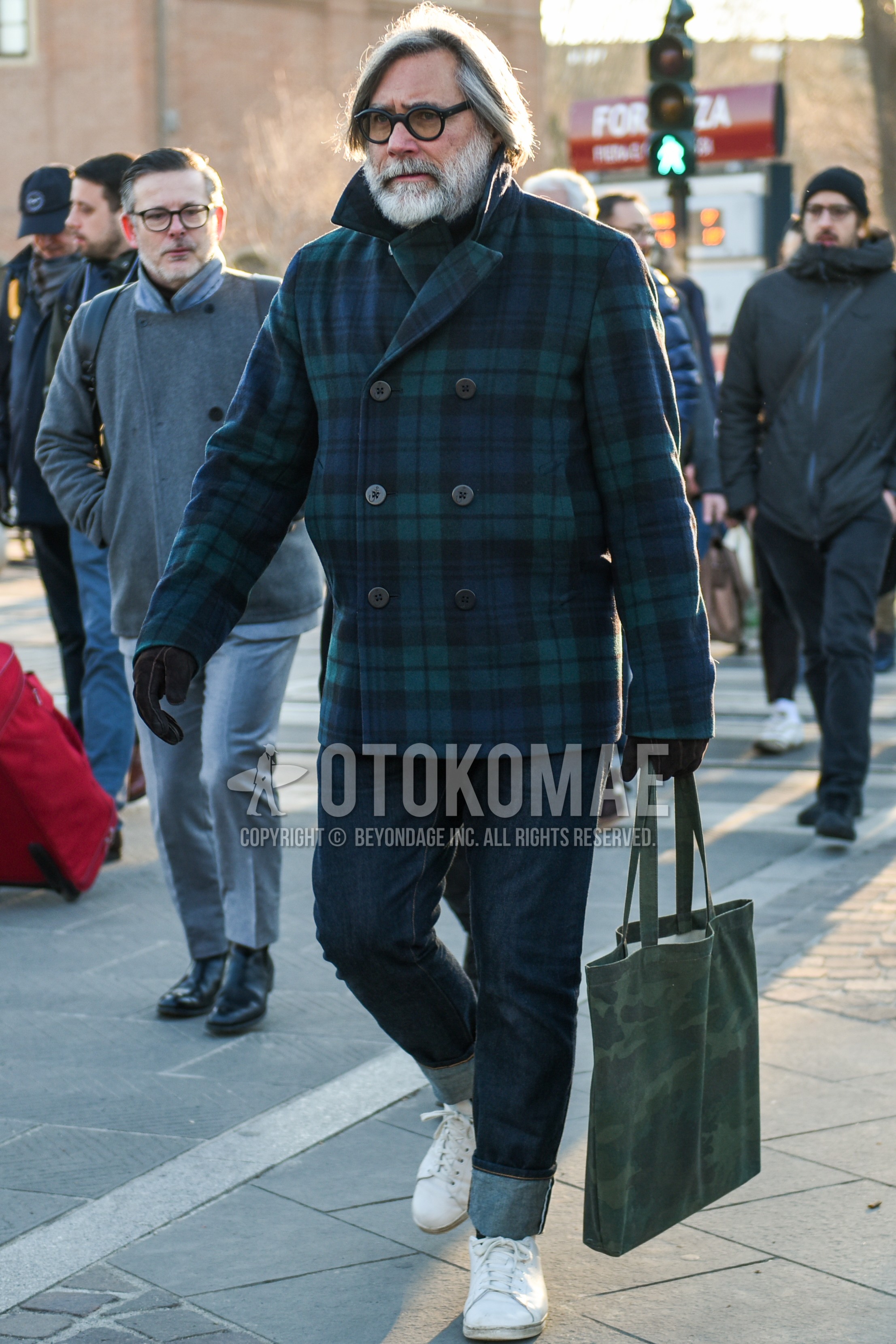 Men's autumn winter outfit with black plain sunglasses, olive green navy check p coat, navy plain denim/jeans, white low-cut sneakers, olive green camouflage tote bag.