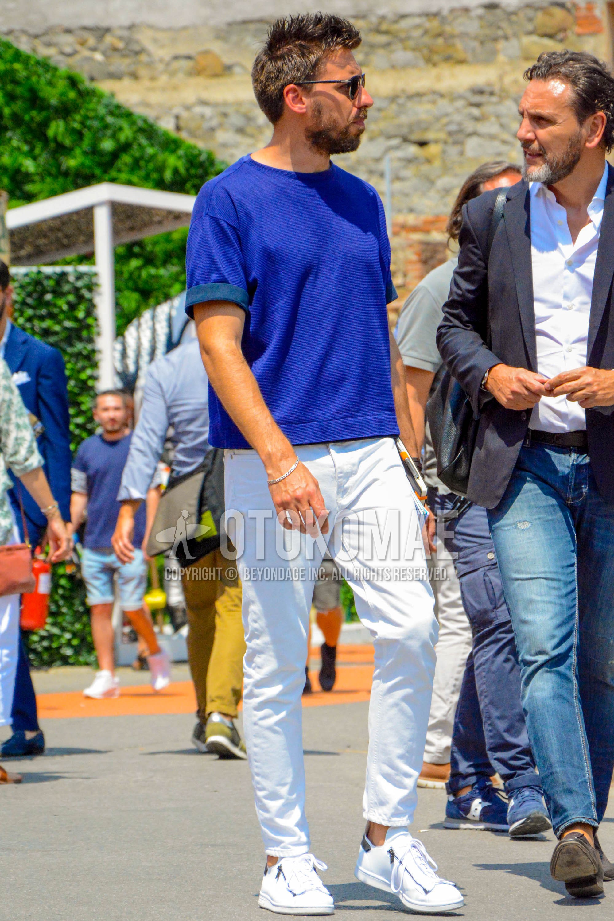 Men's spring summer outfit with black plain sunglasses, blue plain t-shirt, white plain denim/jeans, white low-cut sneakers.